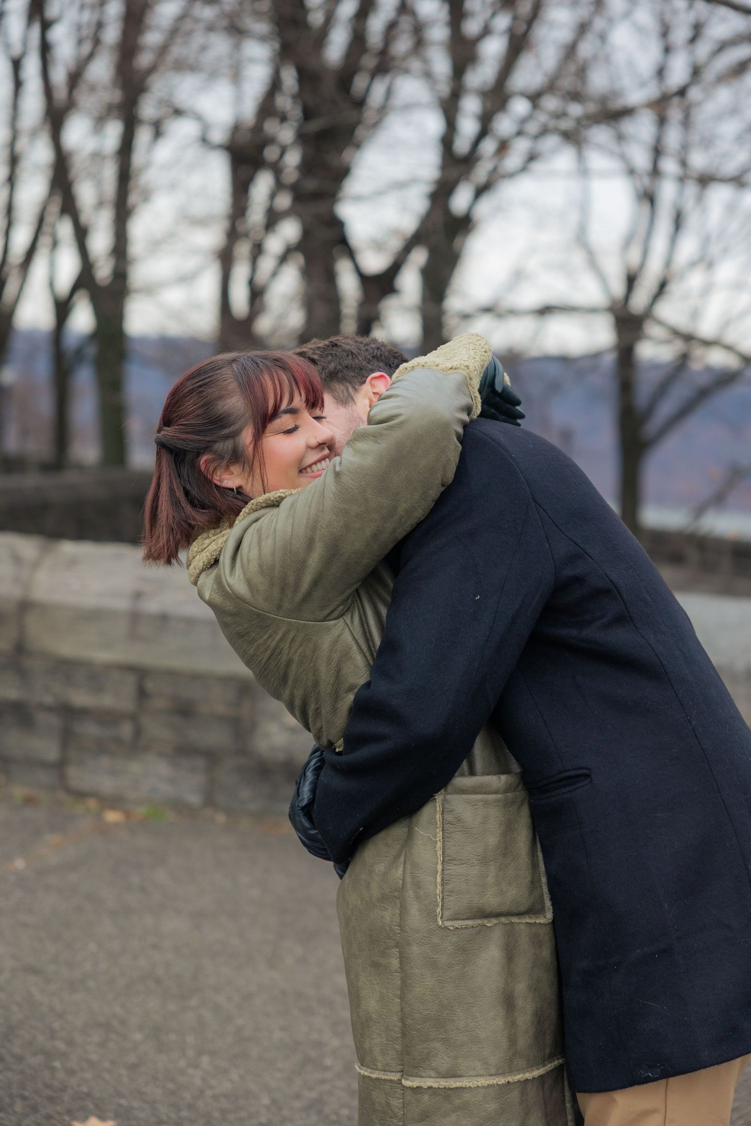 A couple in winter coats share an intimate embrace outdoors on a cold day.