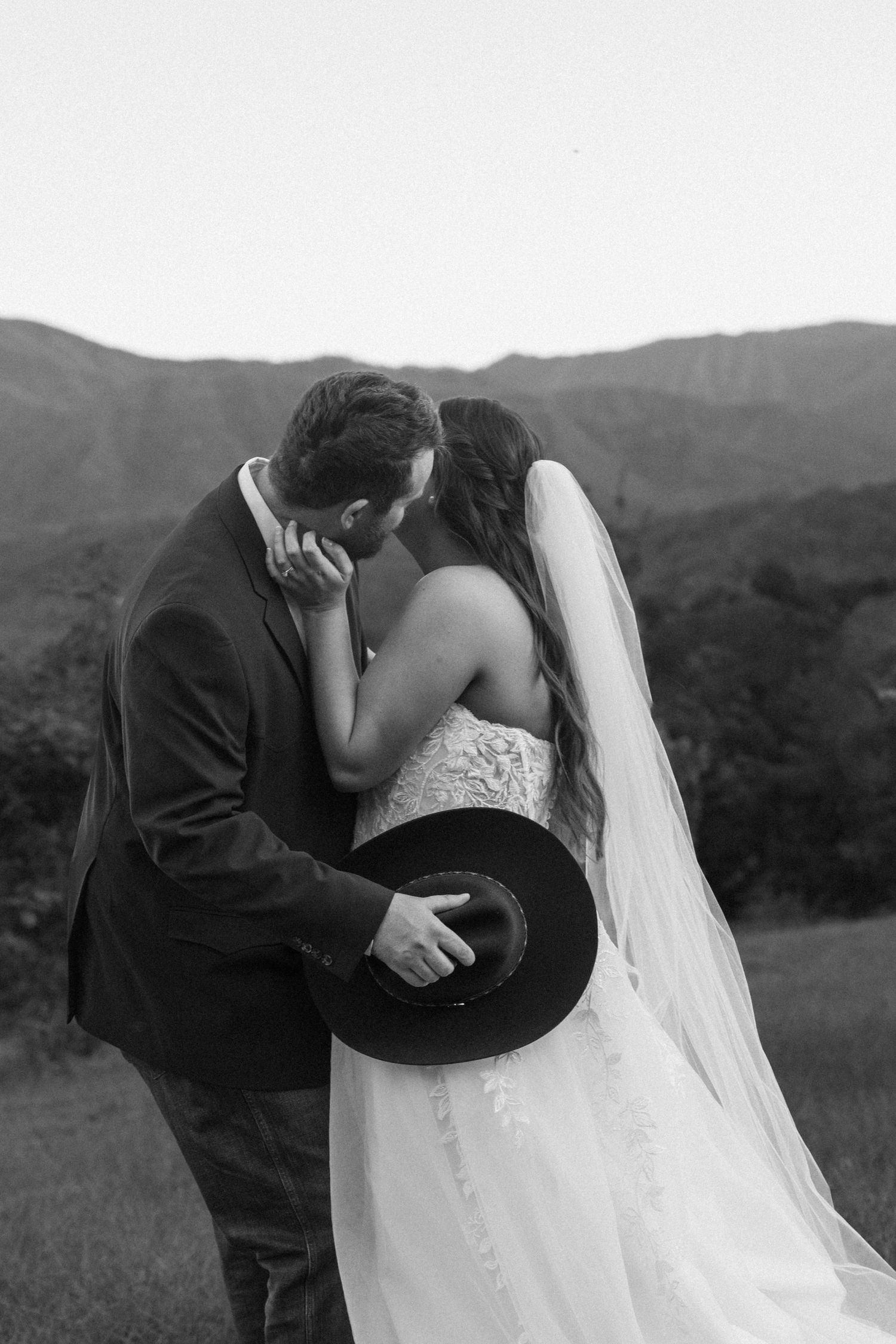 Black and white romantic moment of a couple sharing an intimate moment with mountains in background.
