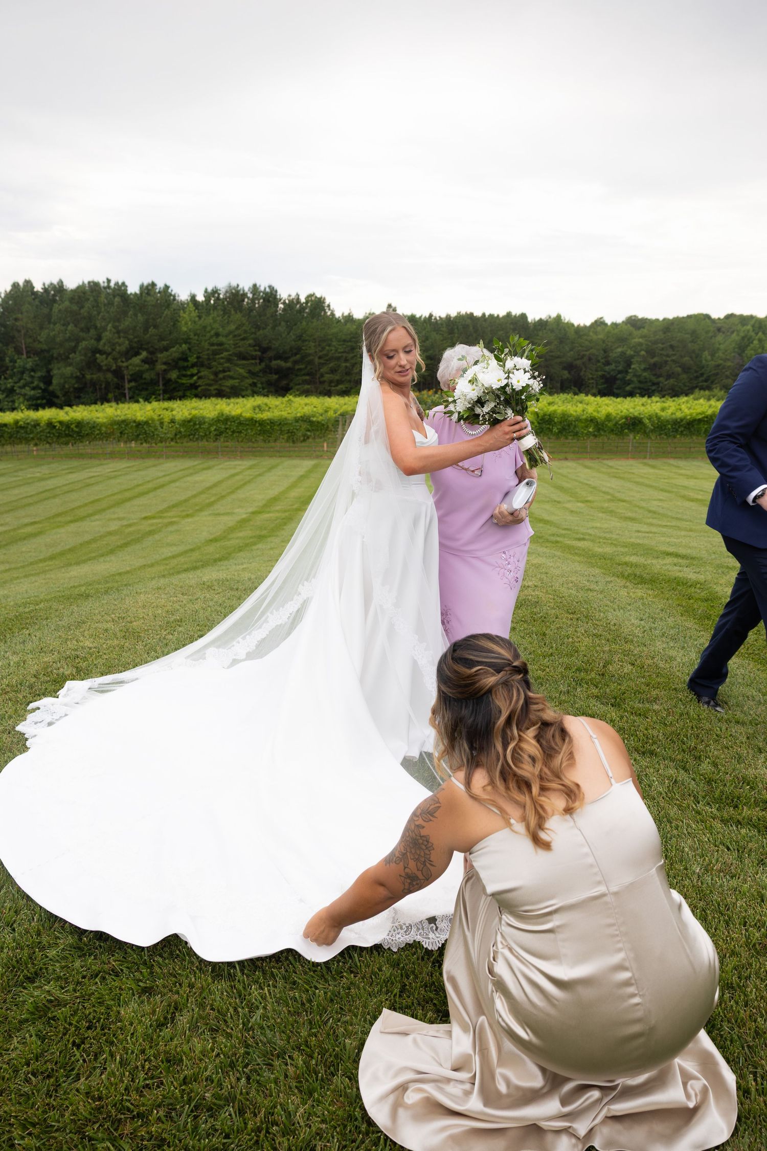 Wedding dress train spreads beautifully across a lush green lawn during an outdoor photo session.