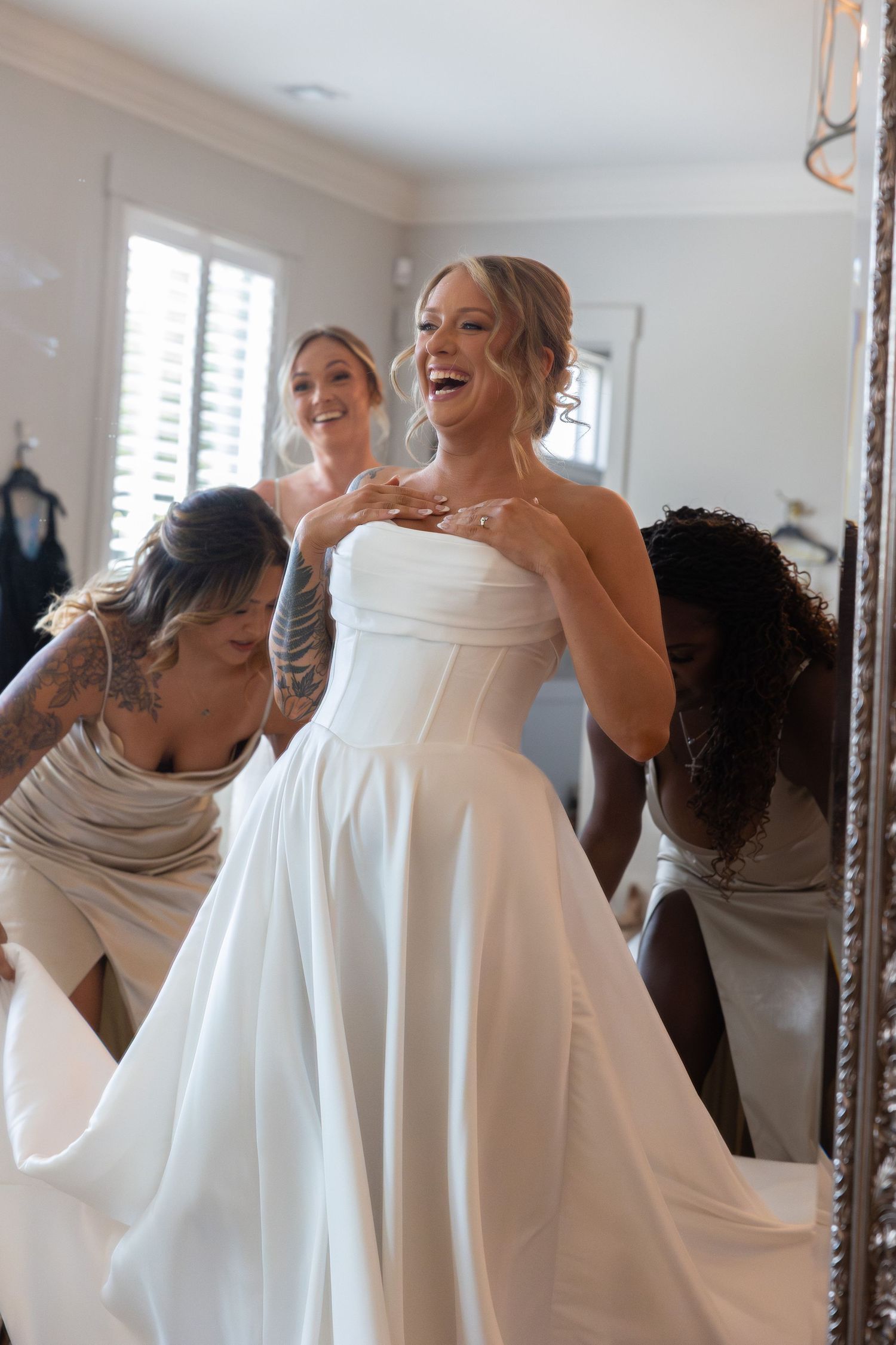 A joyful moment captured in a bridal suite as a group celebrates while helping with wedding preparations.