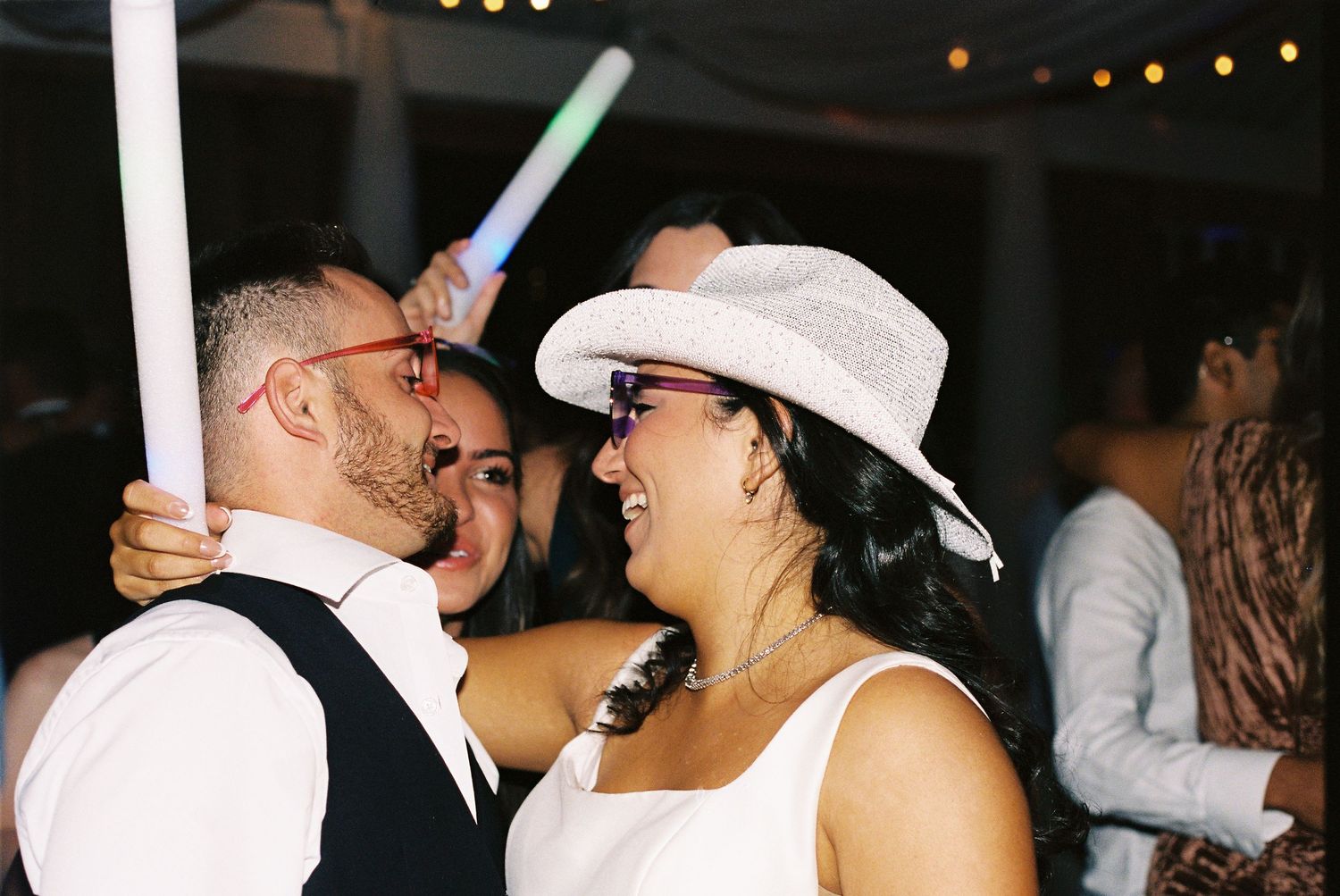 Wedding celebration showing dancers wearing white cowboy hats at an outdoor reception party.