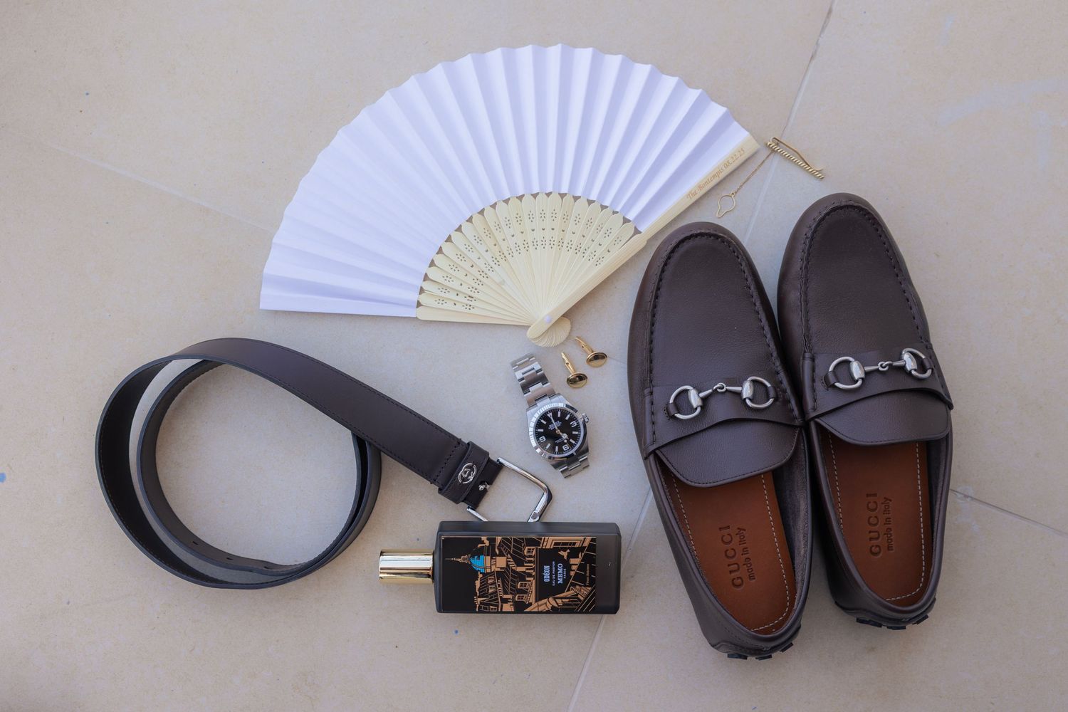 A collection of fashion accessories including sunglasses, folding fans, and leather shoes arranged in a row.
