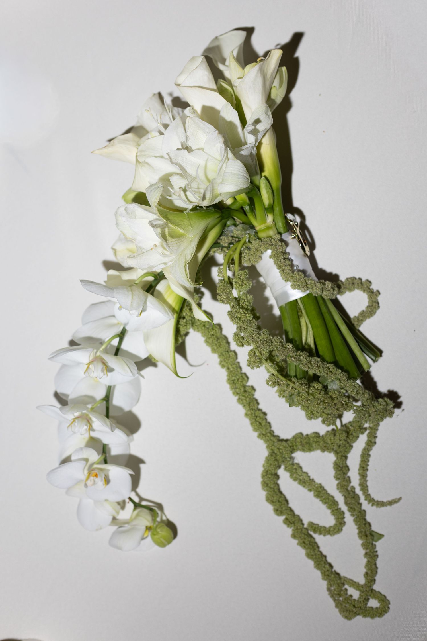A cascading white floral bouquet with delicate green foliage photographed in sequence against a light background.