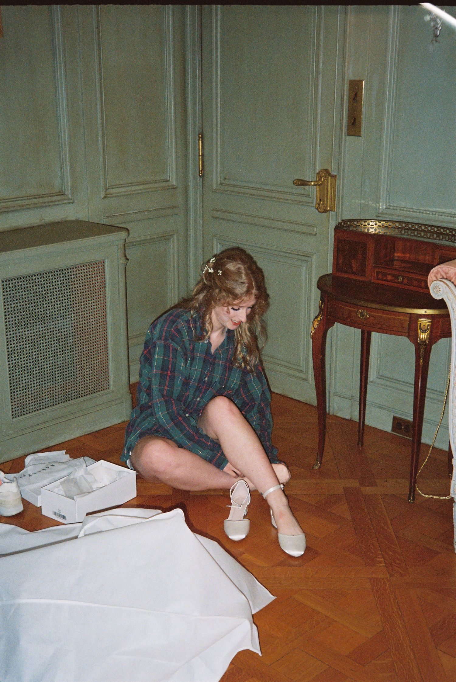 Person in plaid shirt and white socks signs paperwork on hardwood floor.