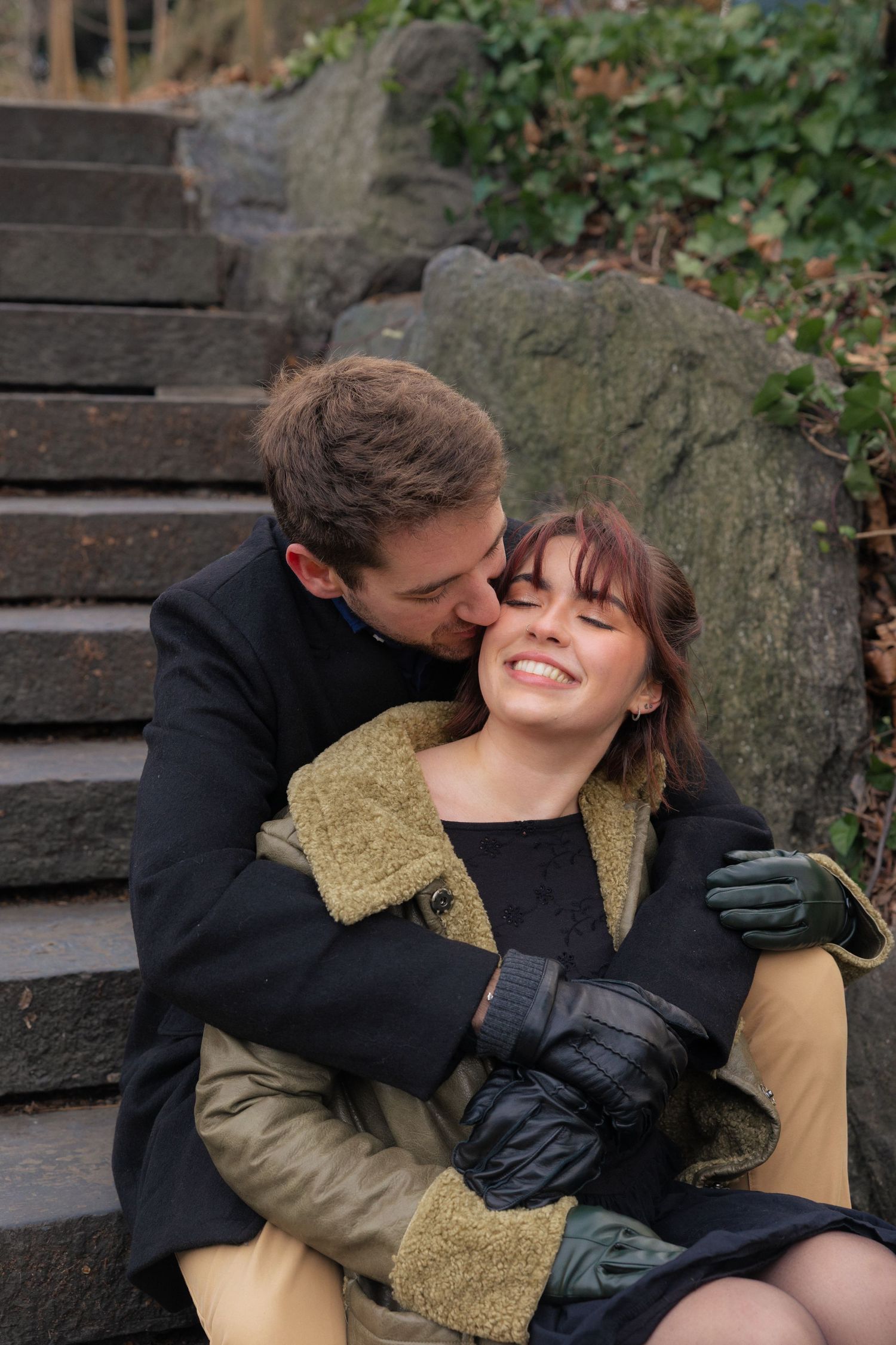 A romantic moment between two people sitting on stone steps surrounded by ivy.
