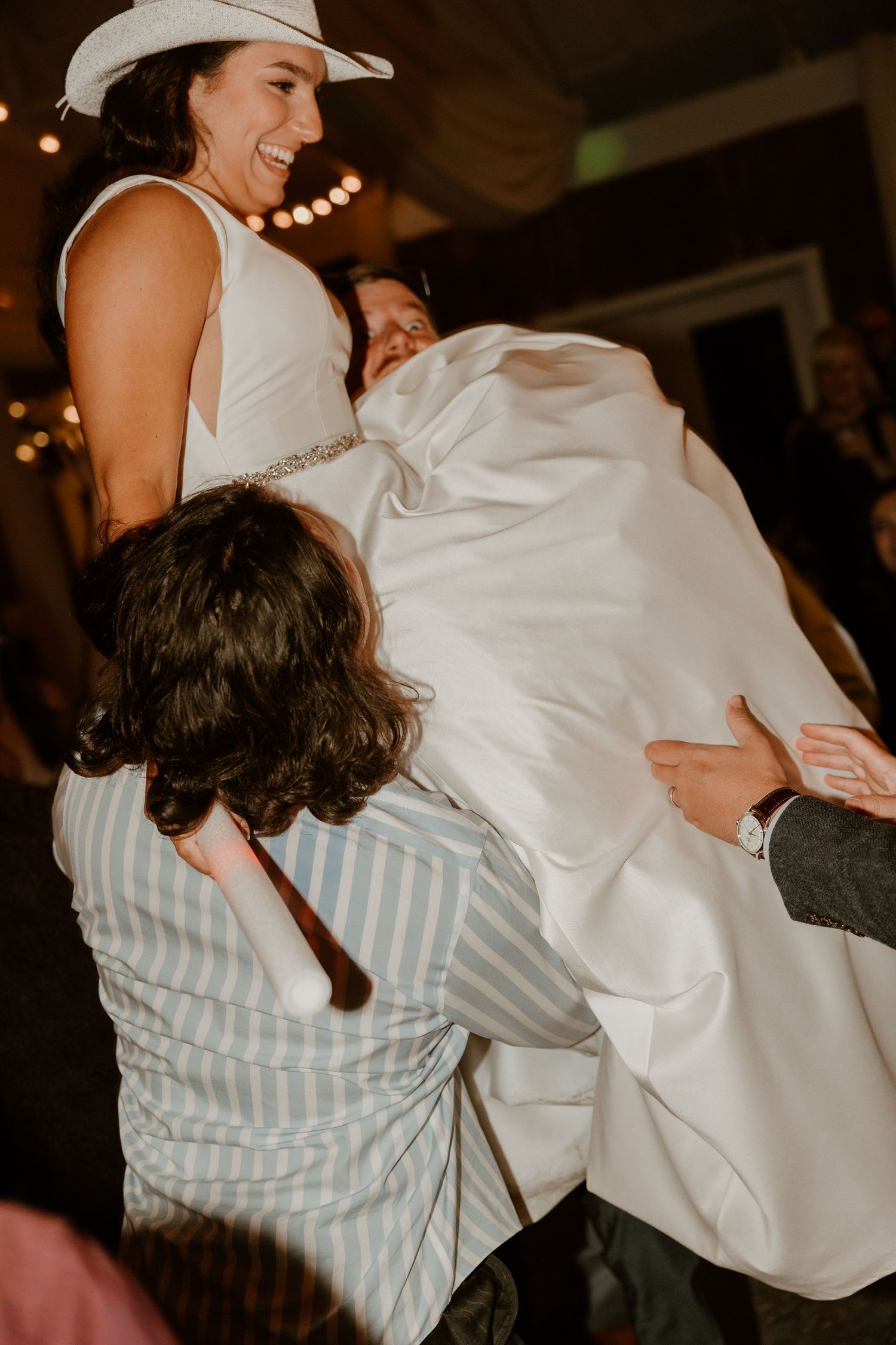 Festive wedding dance party moment with guests lifting and celebrating.