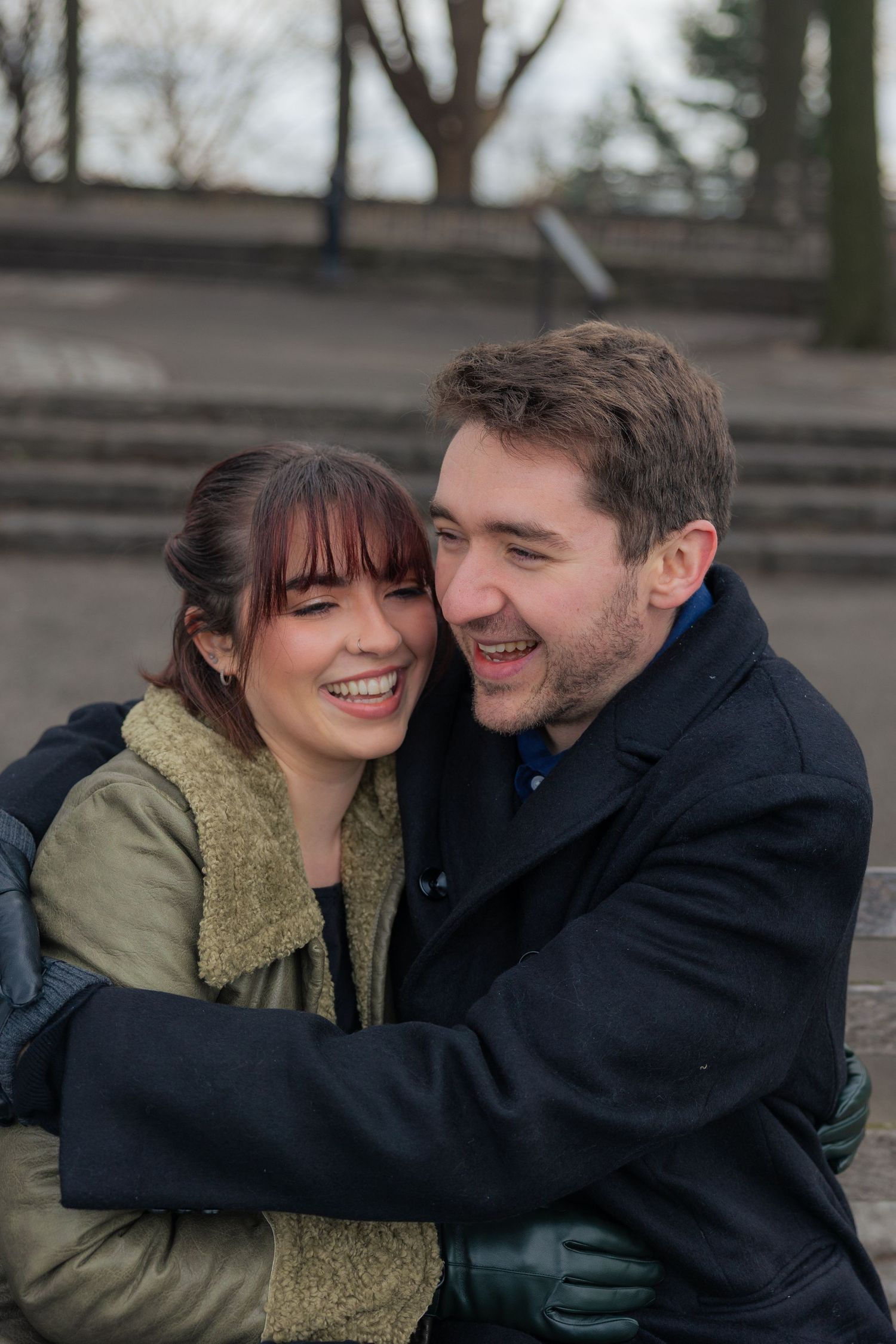 A romantic couple shares tender moments on a park bench in winter, wearing coats and sharing affectionate gestures.