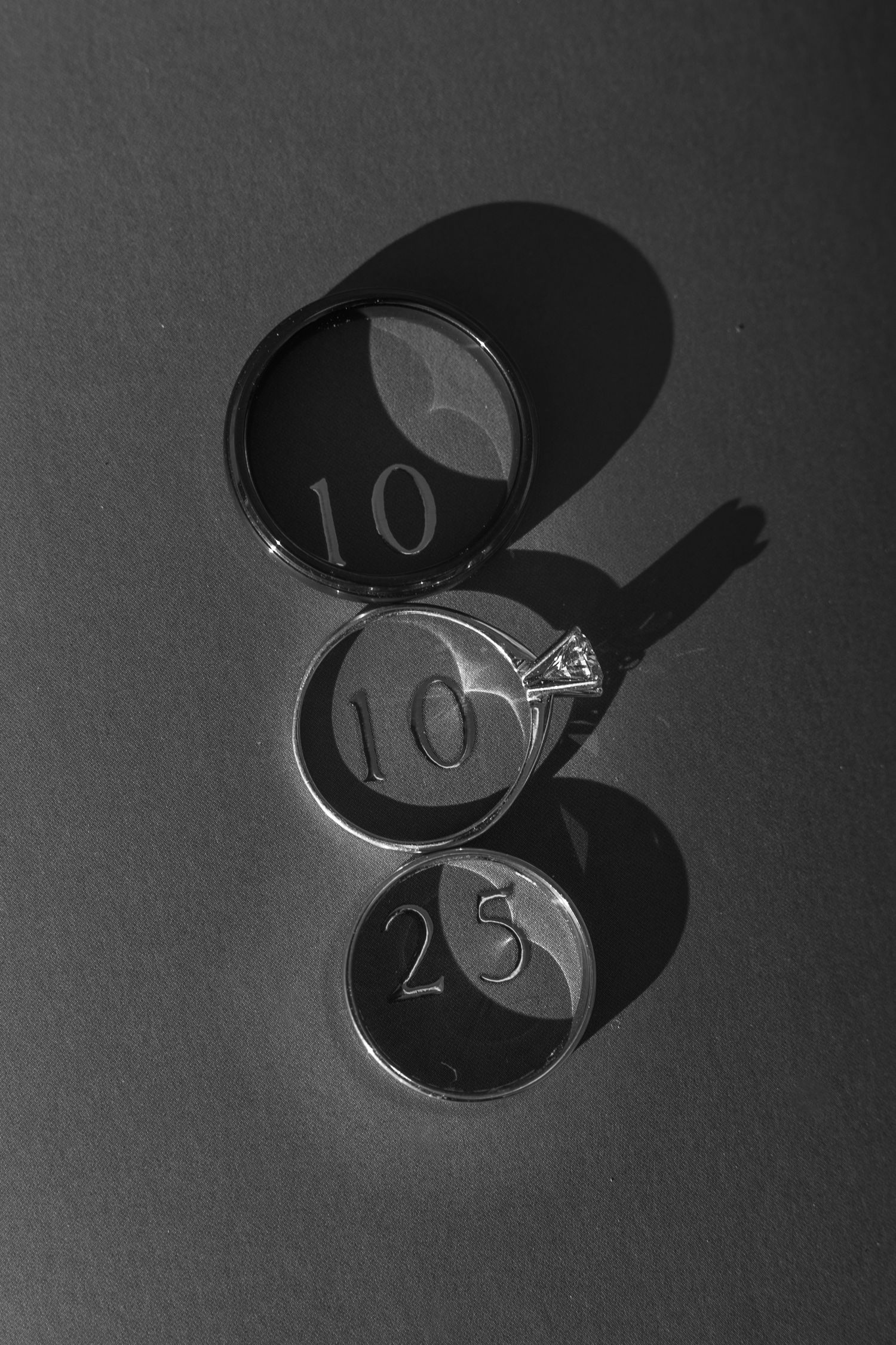 Black and white photo of three circular objects with numbers 10 and 23 casting shadows.