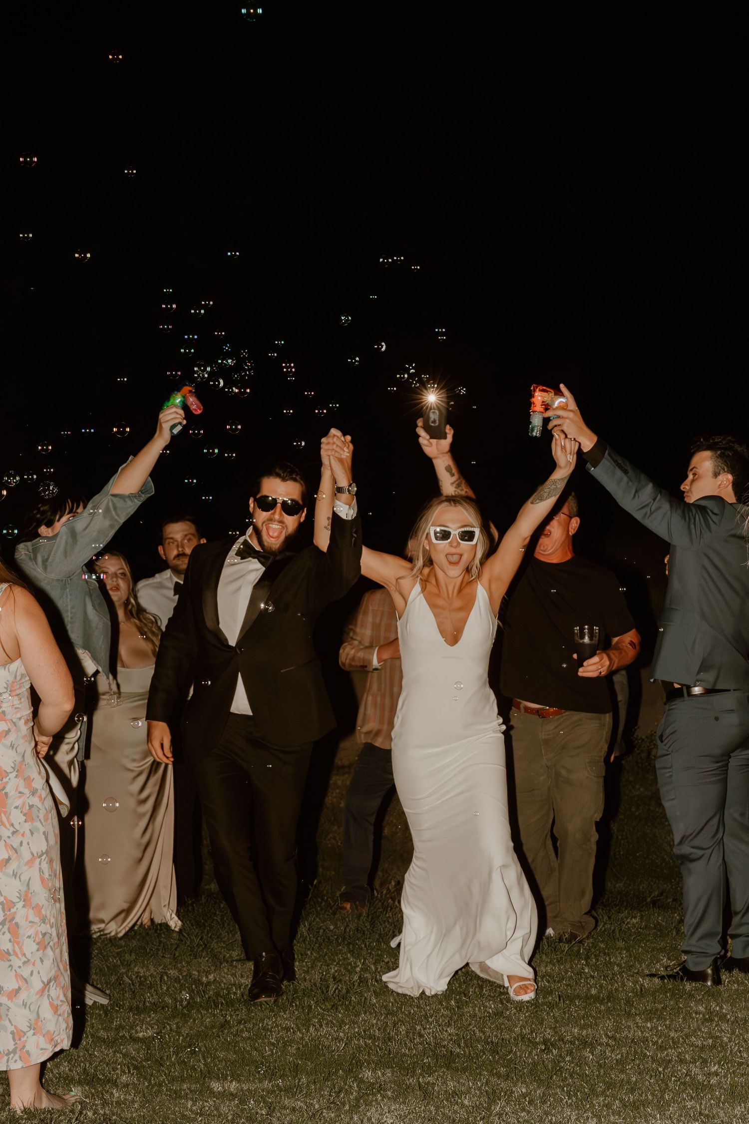 Night celebration with wedding guests holding sparklers under a starlit sky.