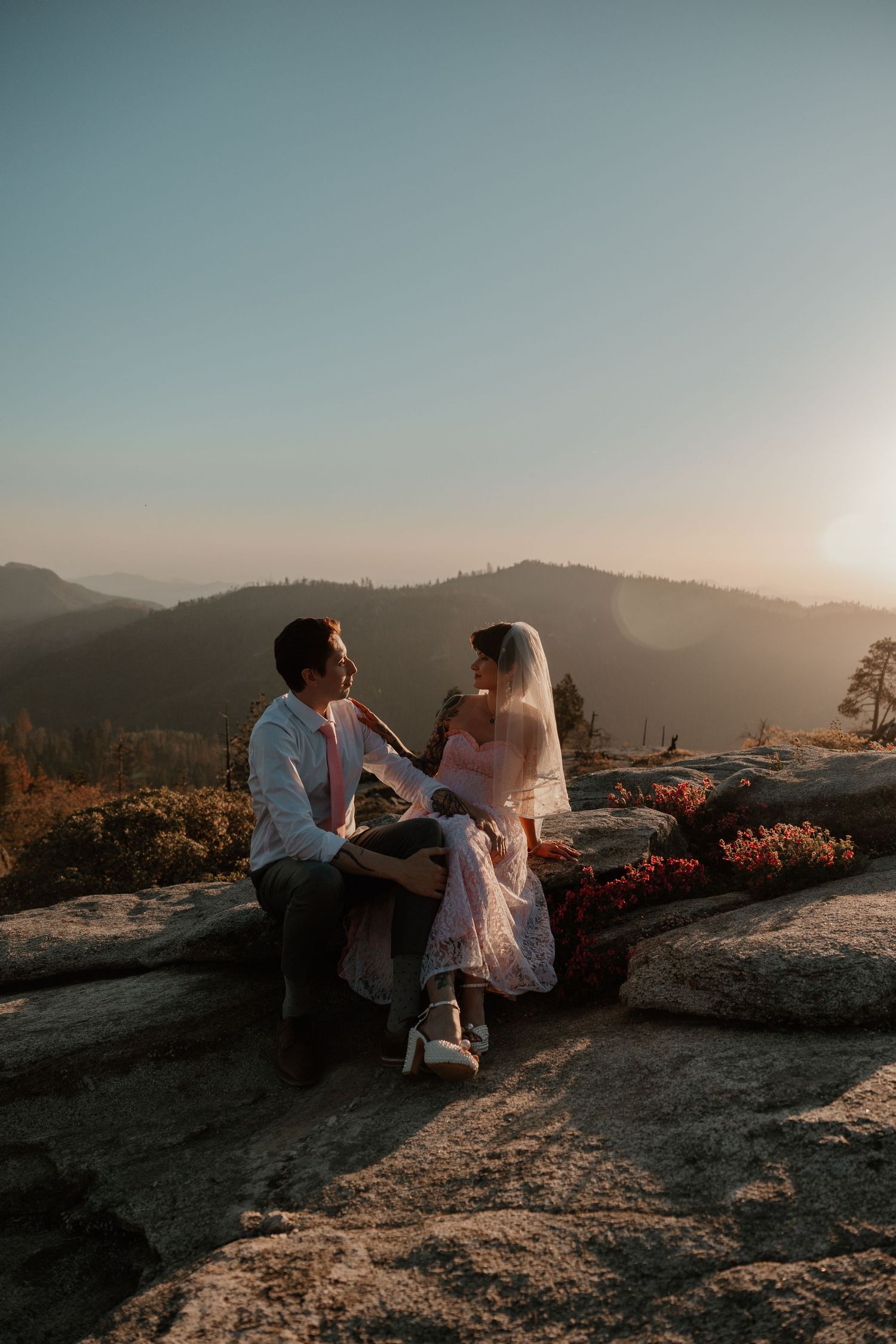 Intimate wedding moment captured on rocky mountain overlook at dusk.