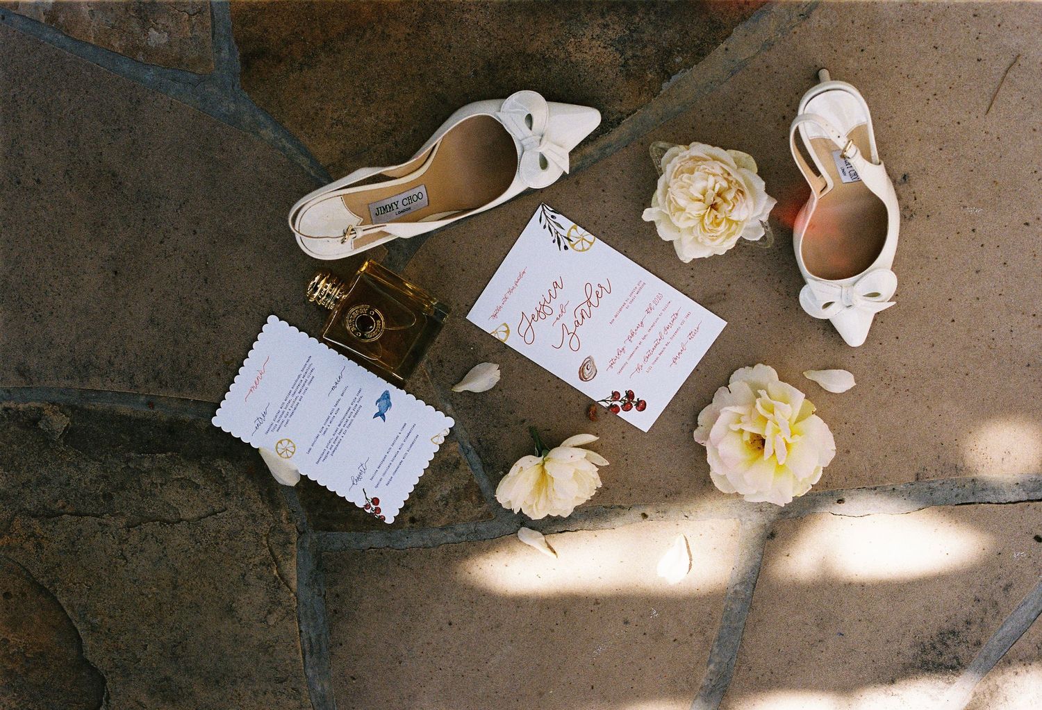 Wedding invitations and decorative elements laid out on a rustic stone surface.