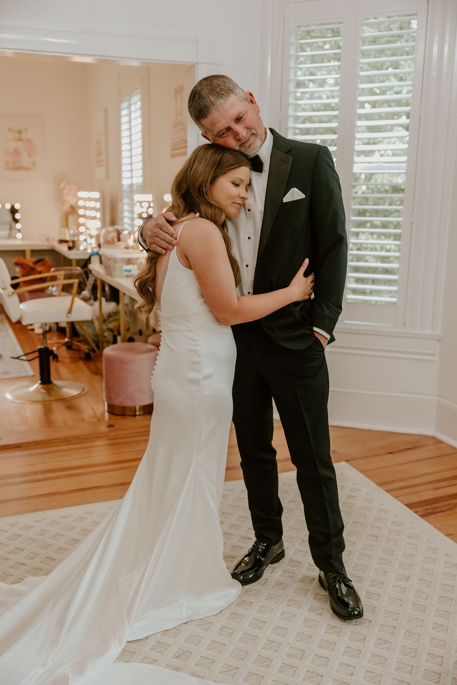 A couple shares their first dance on a patterned carpet in a bright indoor venue.