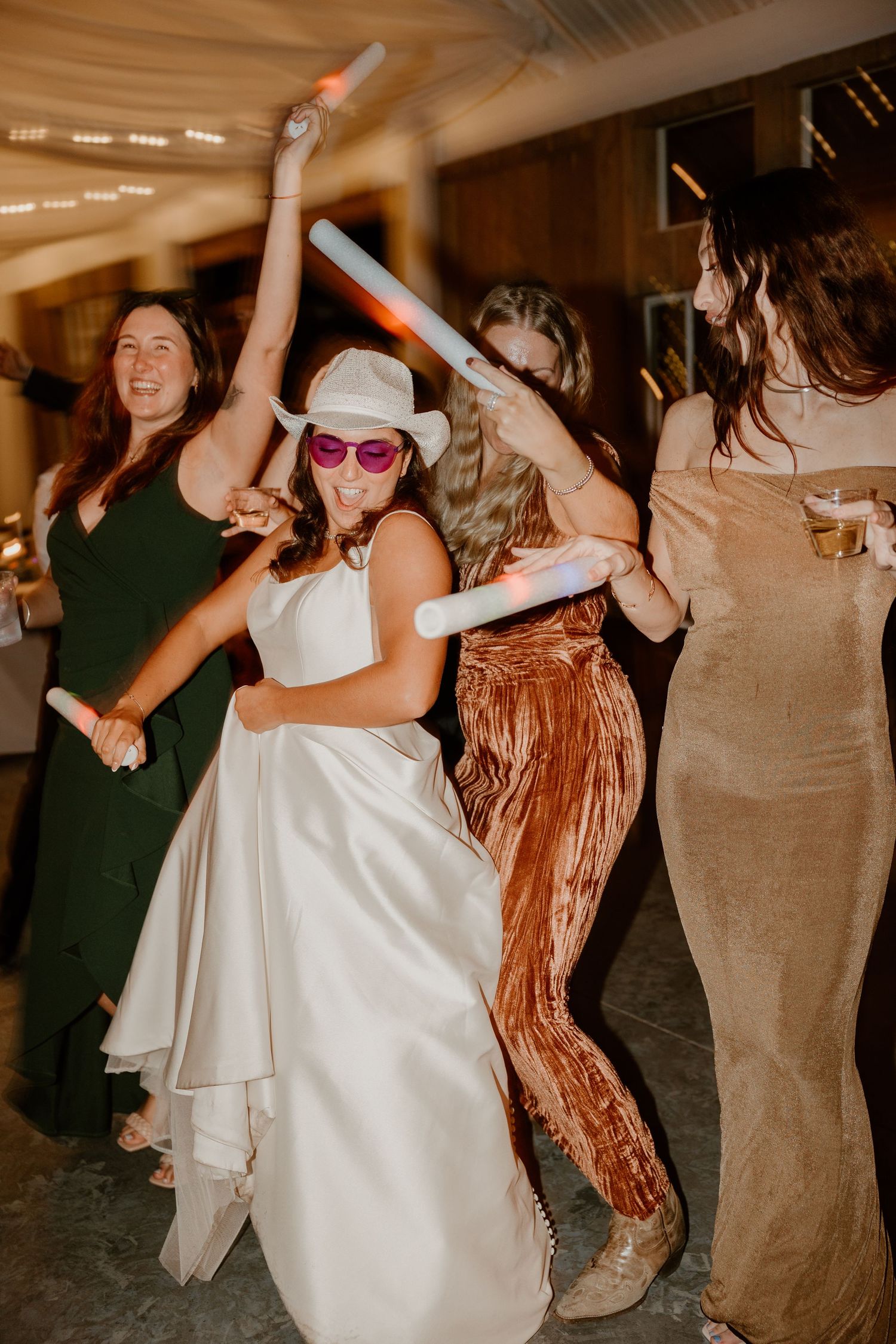 Wedding party dancing with glow sticks and having fun on the dance floor.