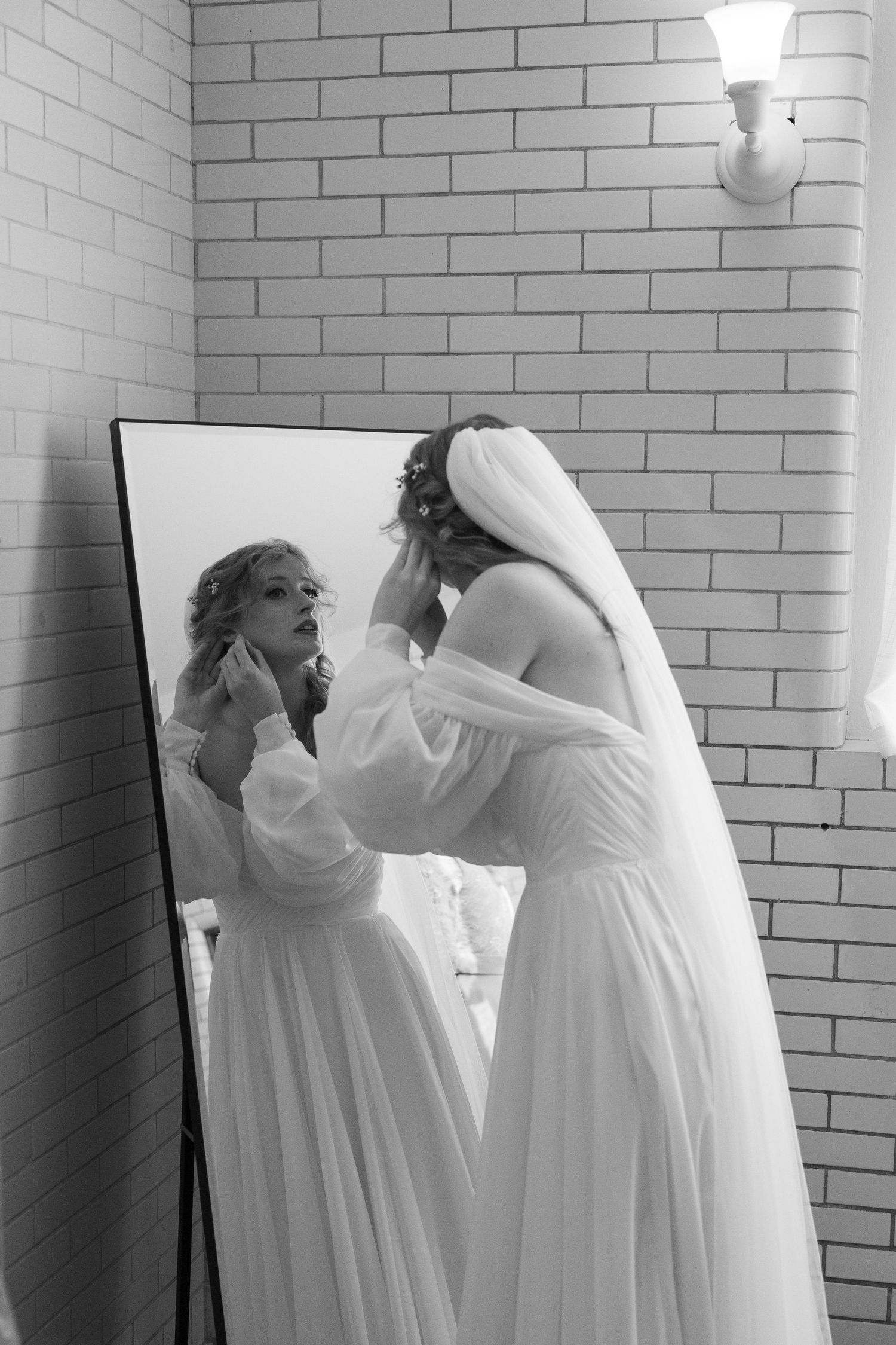 Black and white photo sequence showing bridesmaids helping adjust white wedding dresses against brick wall.