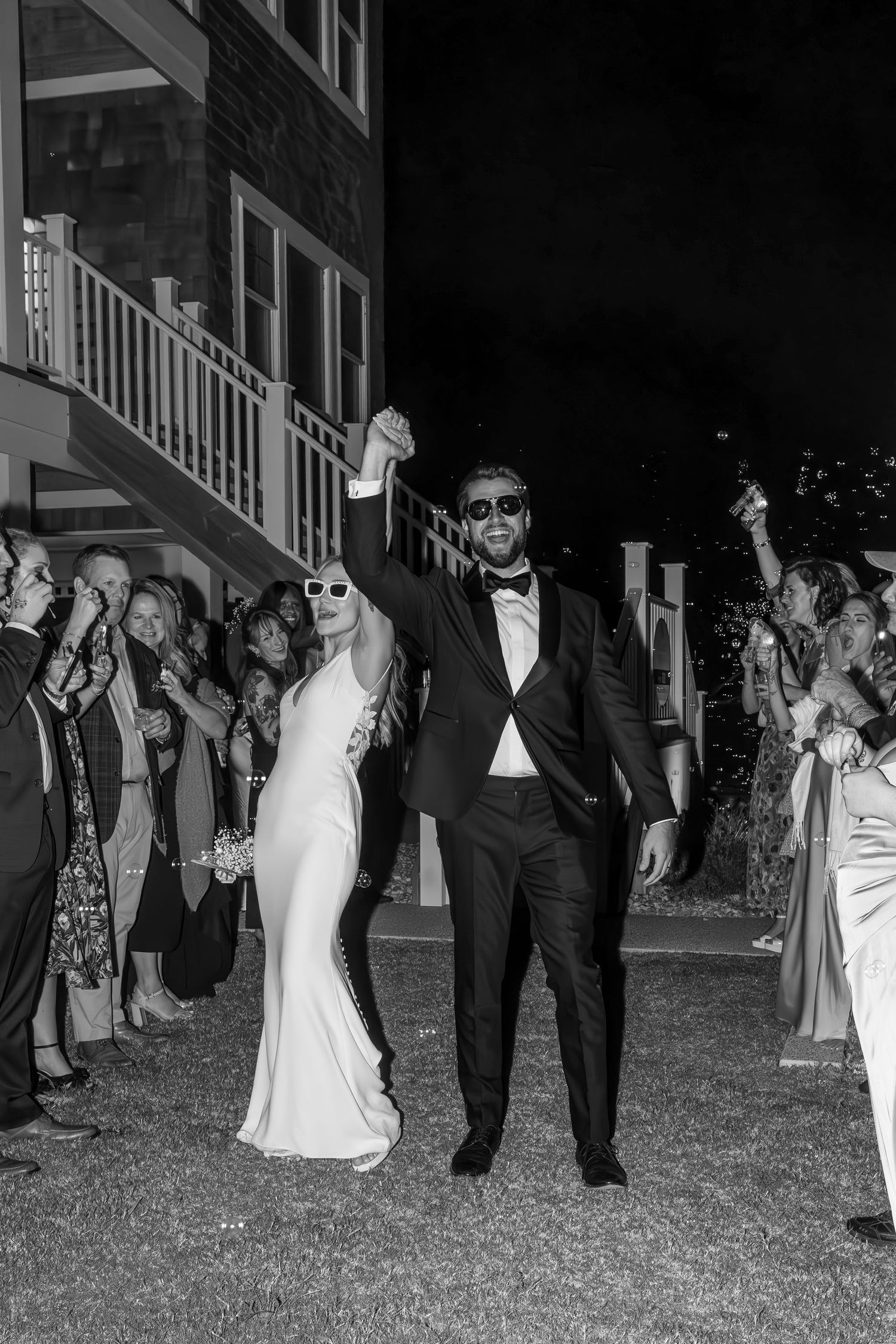 Wedding guests form a celebratory line outside during an evening send-off.