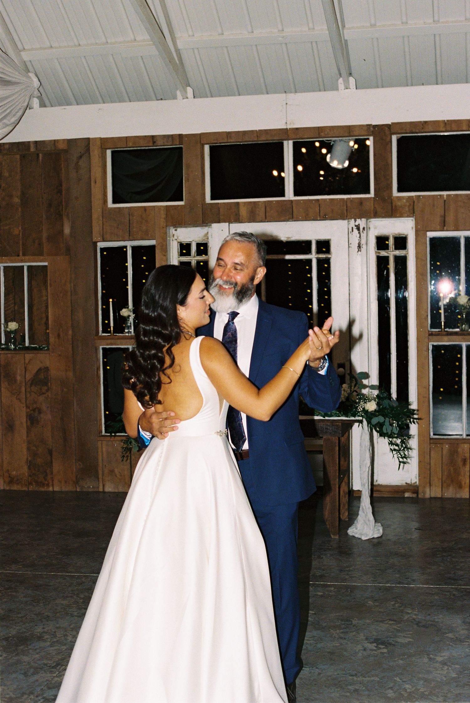 A couple shares their first dance in an elegant rustic venue with wood paneled walls.