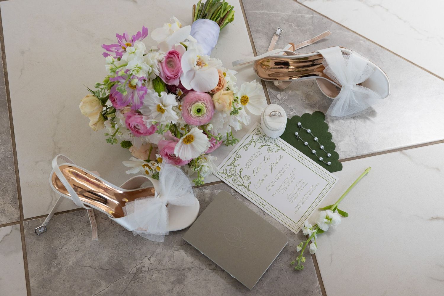 Wedding details including delicate floral arrangements and paper elements displayed on white surface.