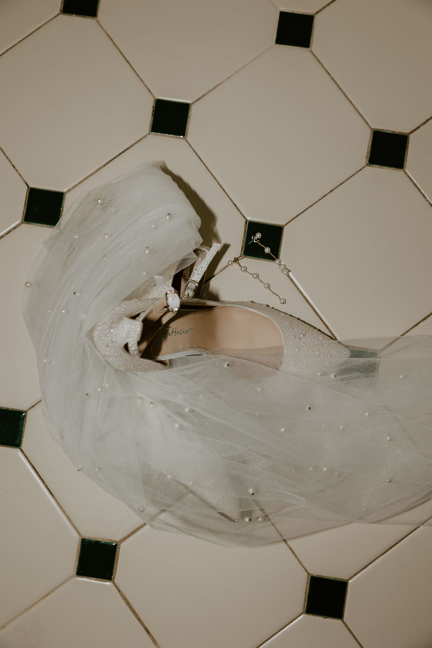 A flowing white wedding veil draped across a geometric black and white tile floor.