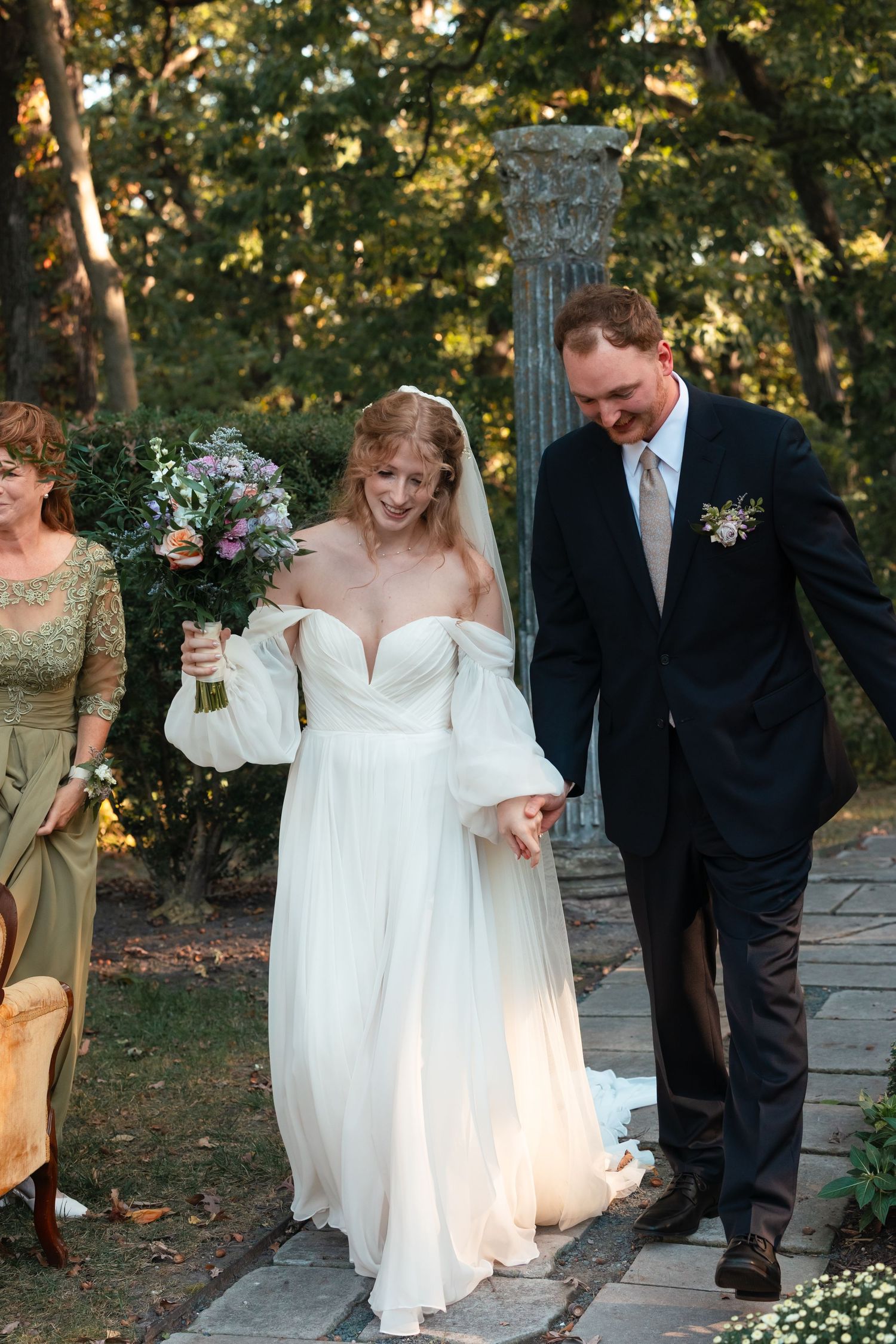 Wedding party walking together on stone pathway during golden hour.