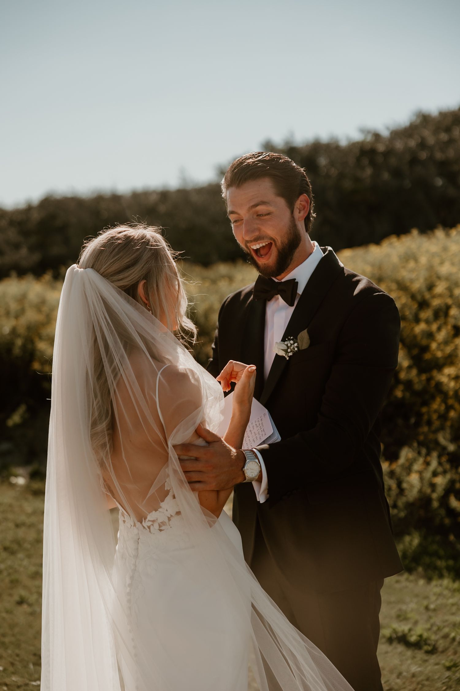Candid wedding moment showing reactions during the vow exchange in a scenic outdoor setting.