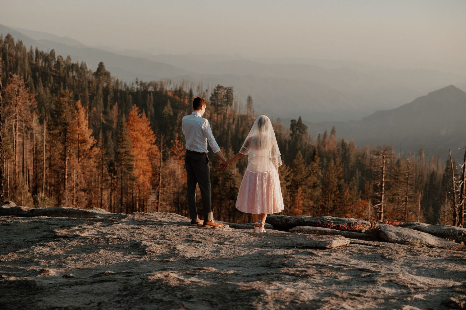 Dramatic mountain landscape provides backdrop for outdoor wedding photo session at sunset.