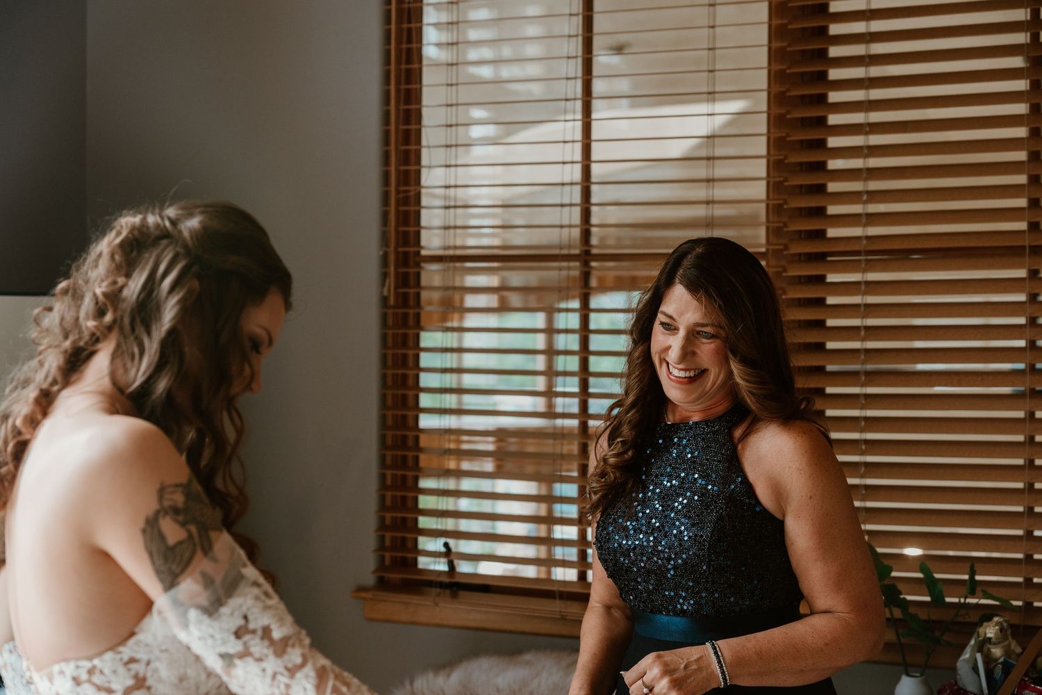 Two people share a joyful moment while getting ready for a wedding ceremony.
