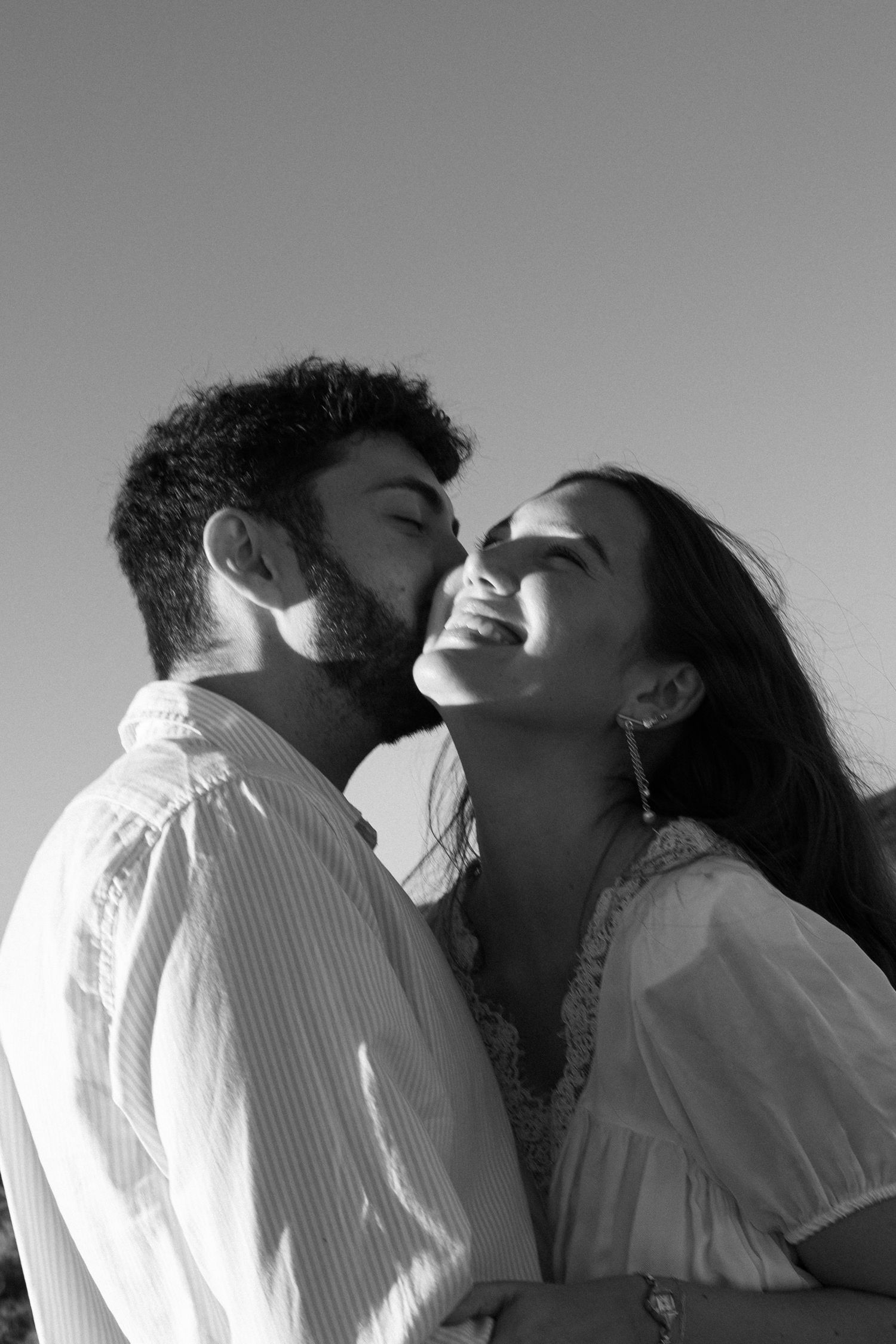 A black and white portrait captures an intimate moment between a couple in white shirts.