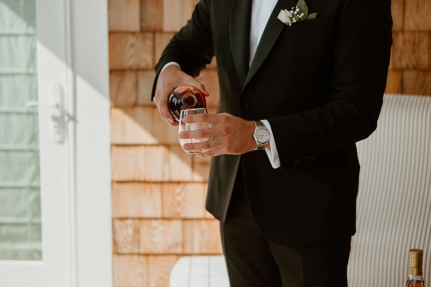 Closeup of hands in black suit pouring a drink at a formal event.