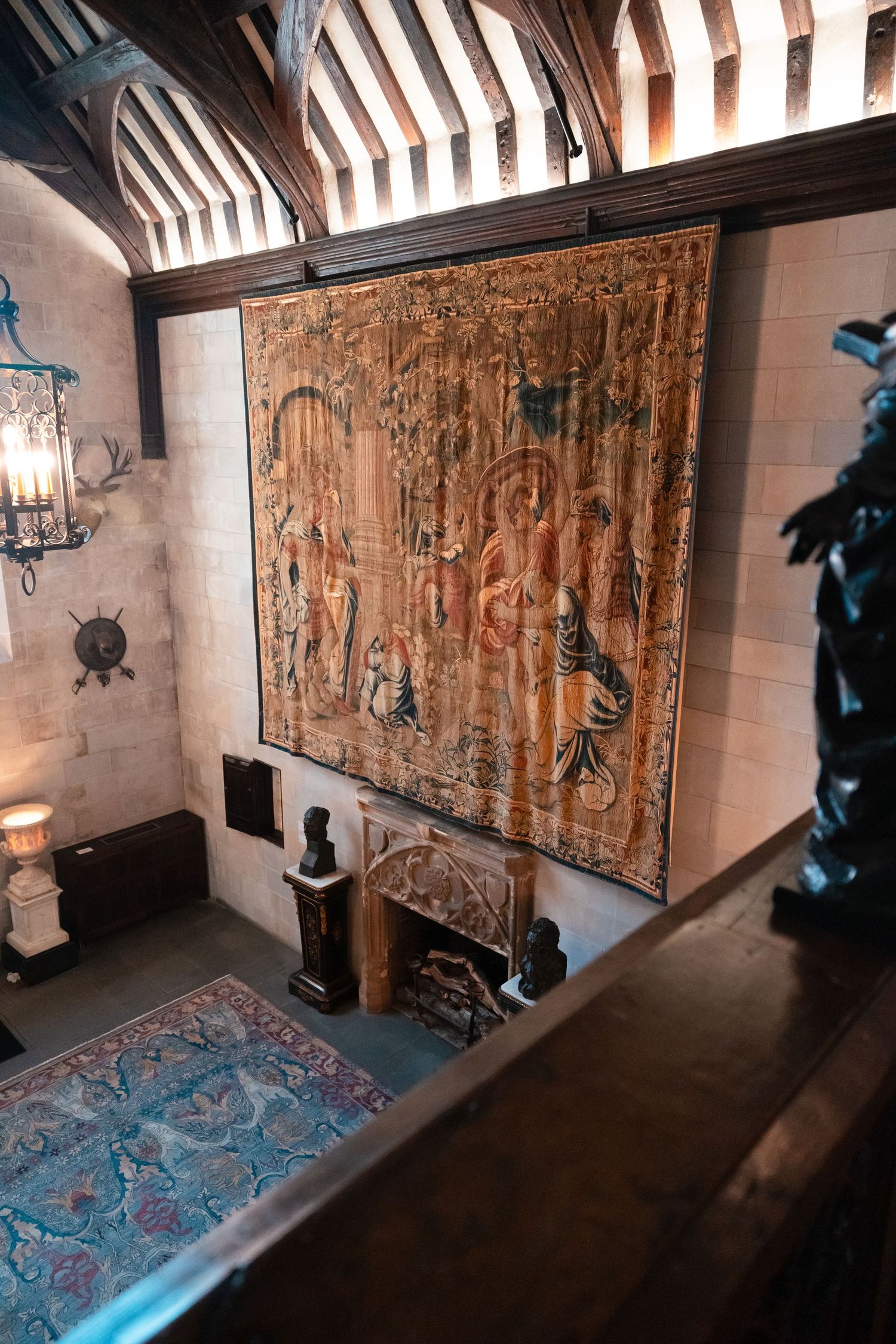 Vintage tapestries with medieval scenes hang on stone walls in a dimly lit castle room.