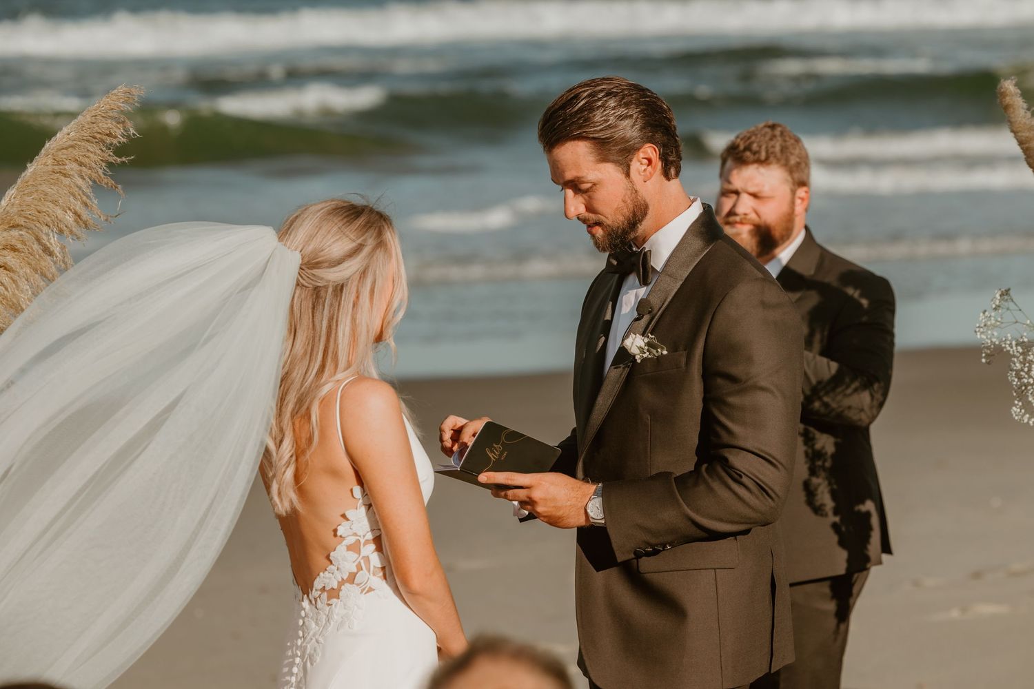 Intimate beach wedding ceremony with couple exchanging vows by the ocean waves.