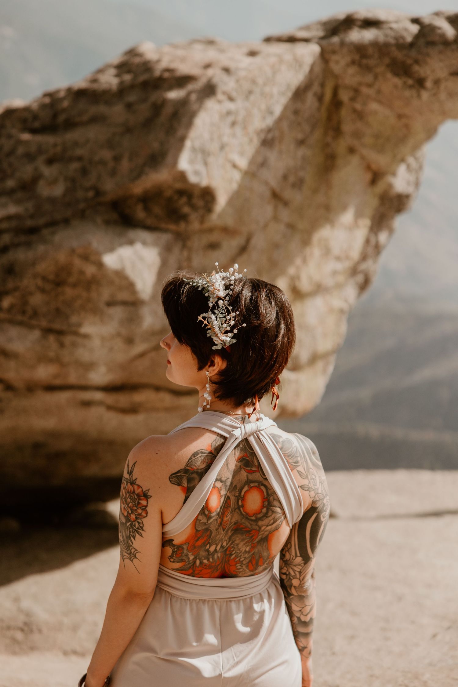 Back view of a wedding dress showing intricate tattoo art through sheer fabric.