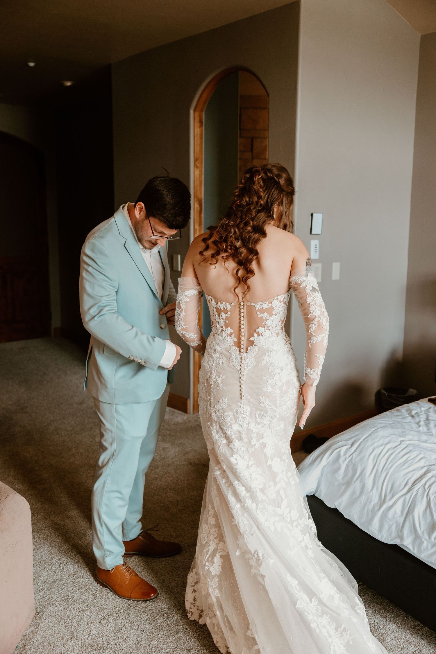 A wedding day first look moment between two people in a bedroom setting.