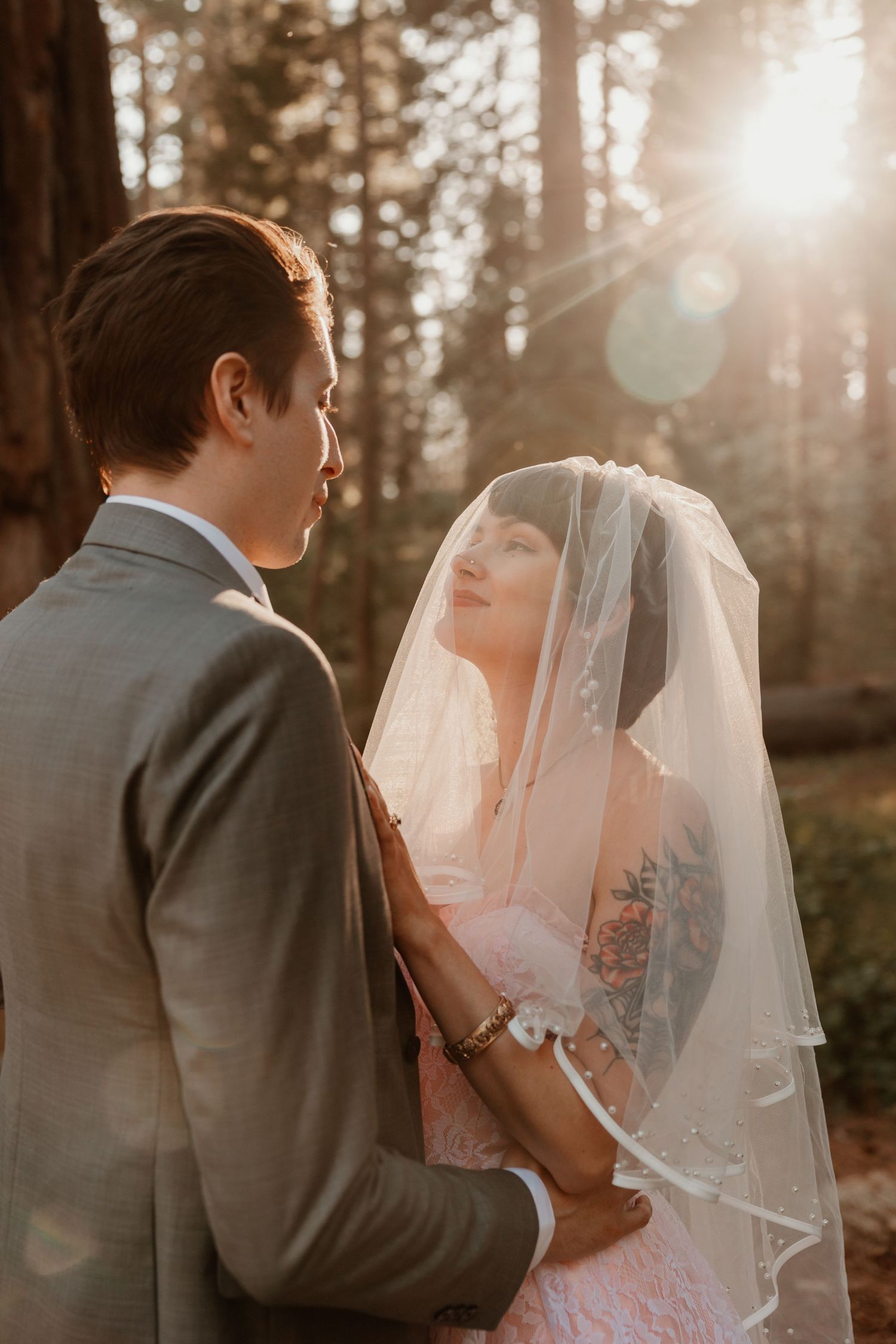 An intimate wedding moment captured in golden sunset light through the forest trees.