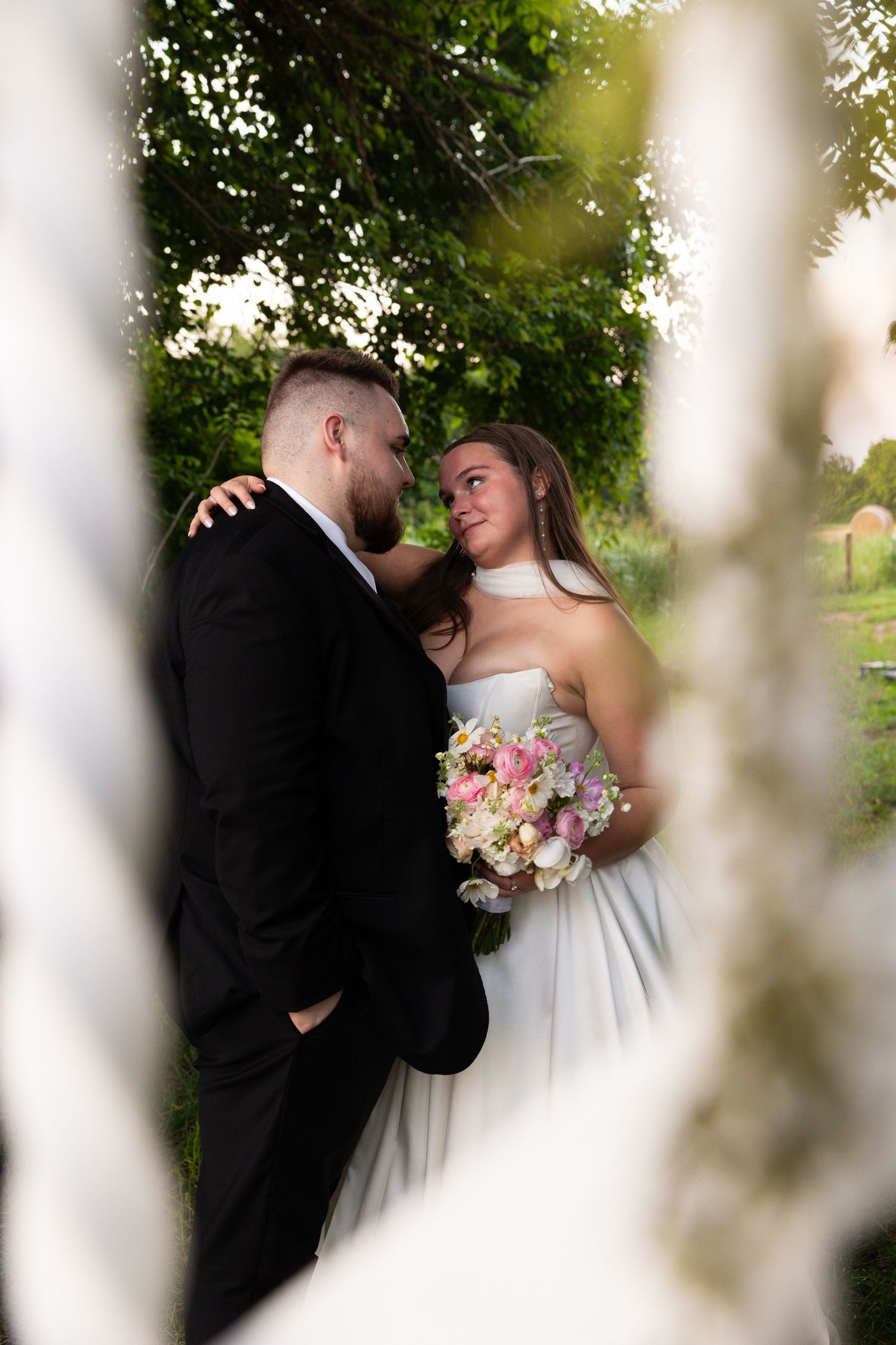 Romantic wedding portrait framed through white columns with soft natural lighting.