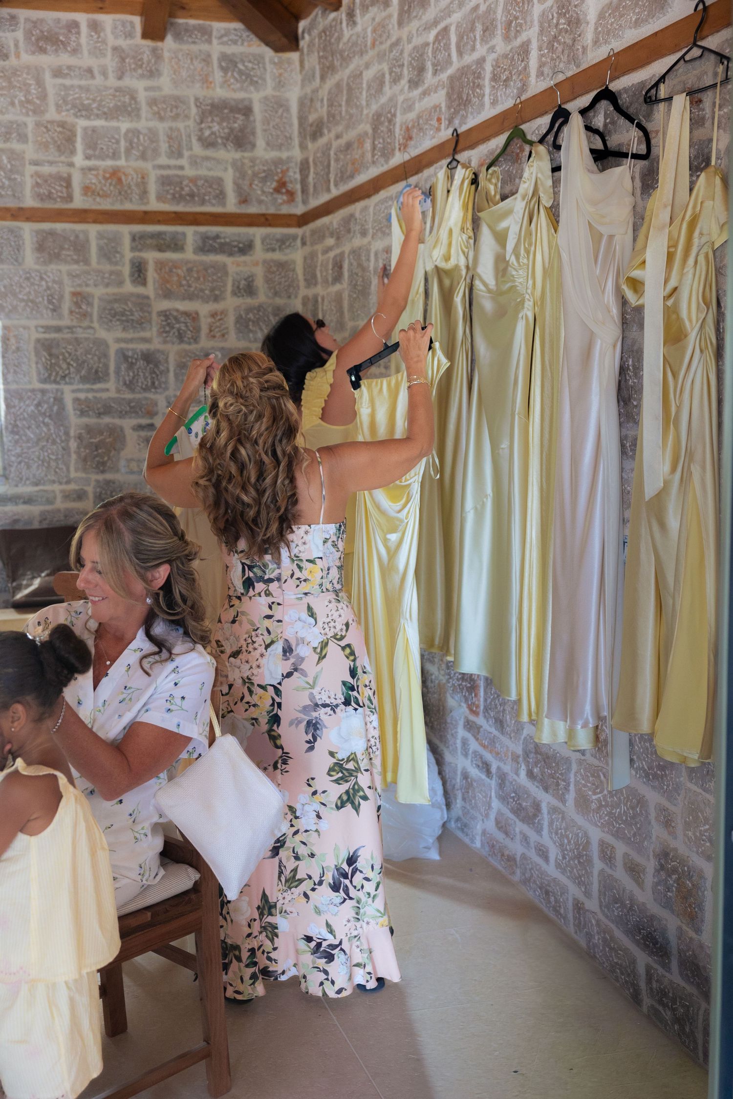 Multiple views of people hanging yellow curtains on a stone wall in a room.