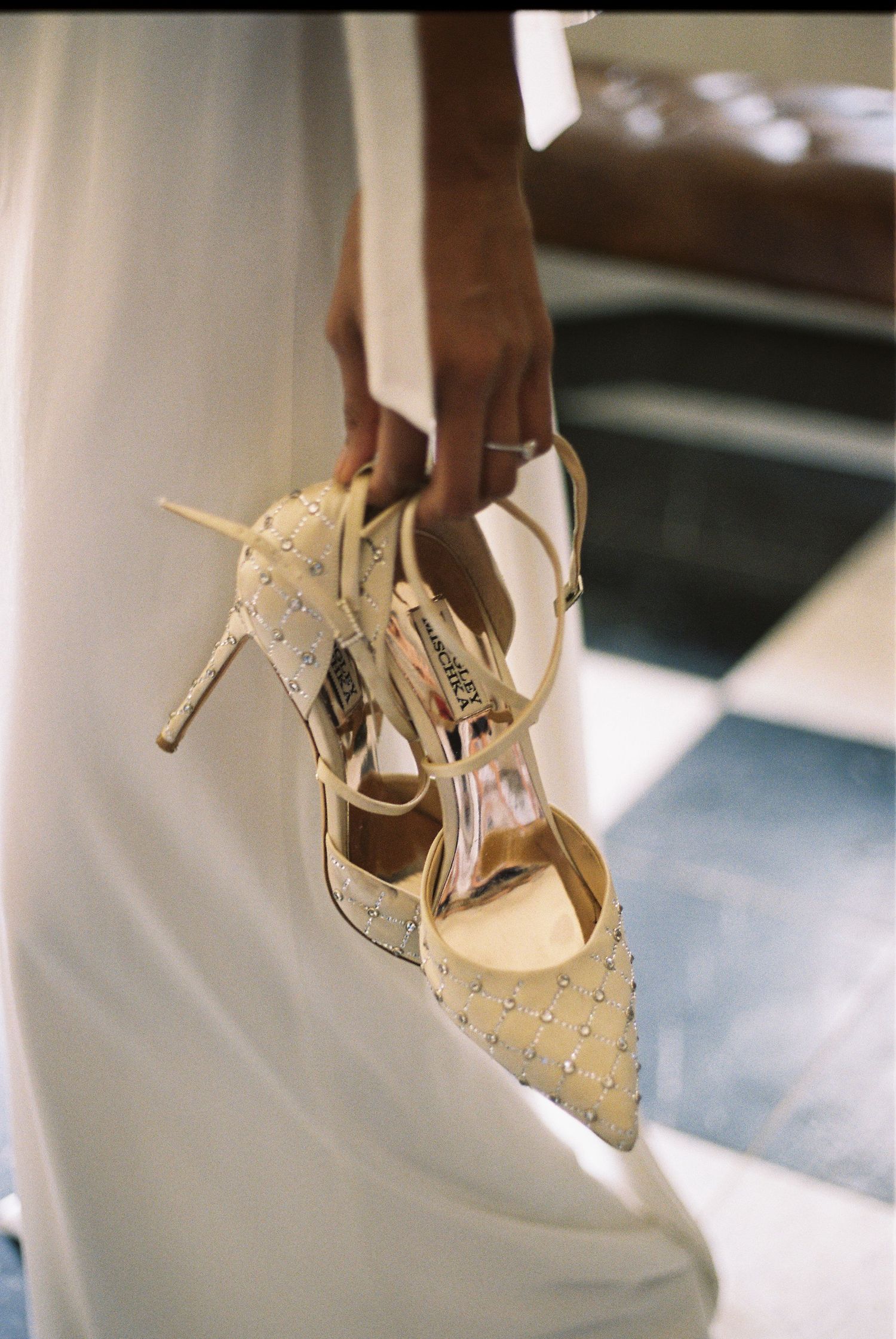 Bride's embellished wedding shoes photographed against white fabric.