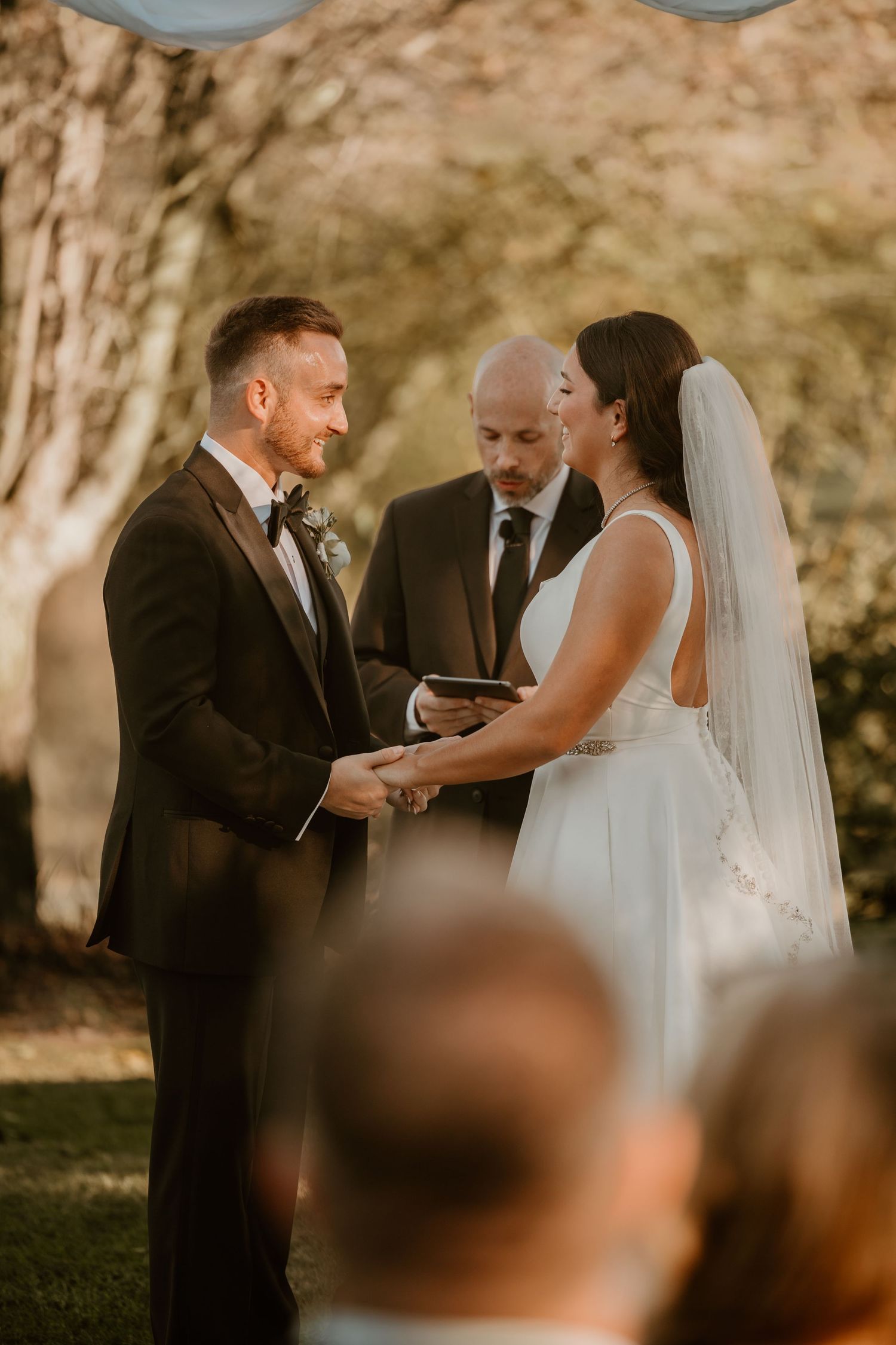 An intimate outdoor wedding ceremony with a couple exchanging vows under natural lighting.
