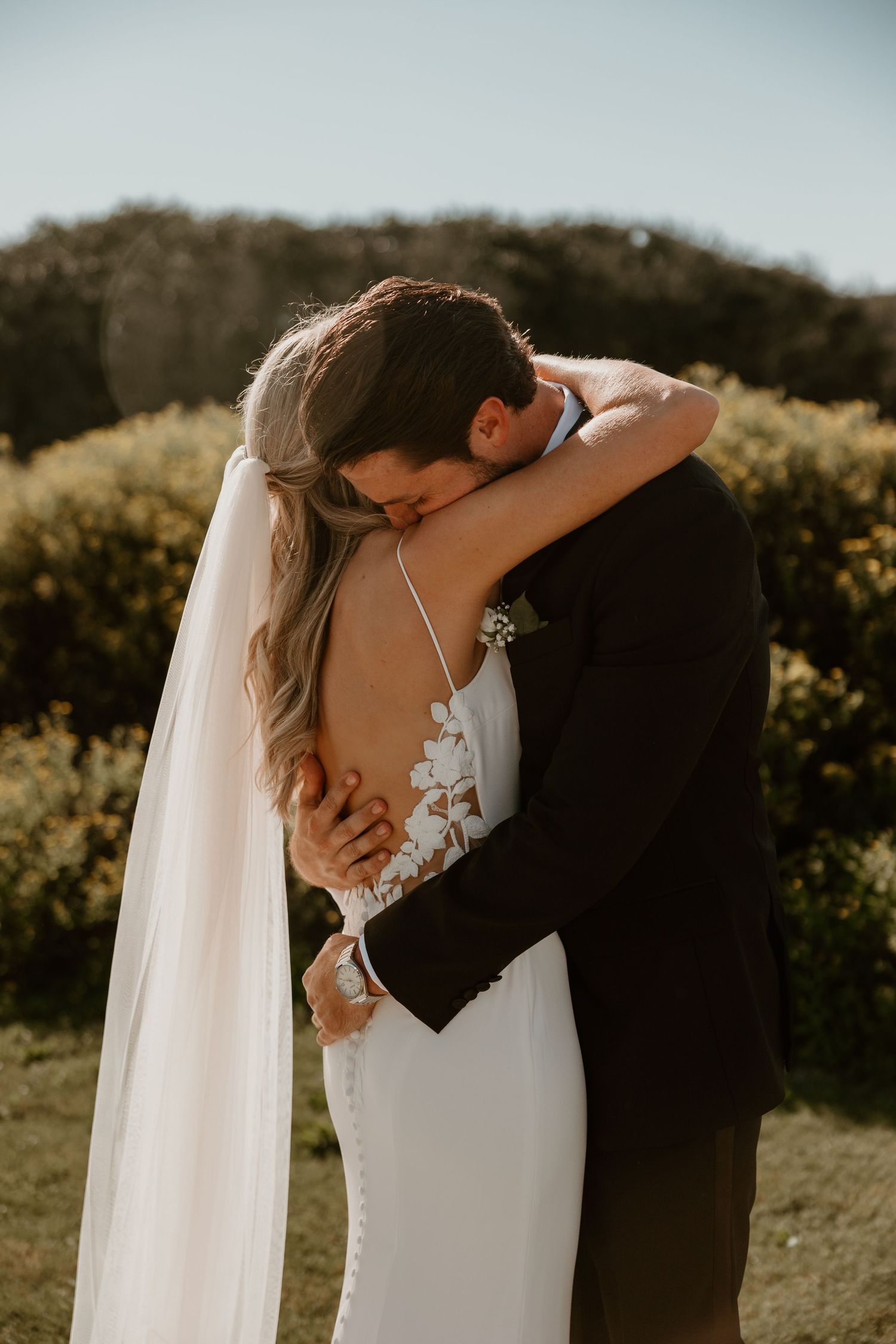 Romantic wedding portraits captured in golden sunlight against a natural landscape.