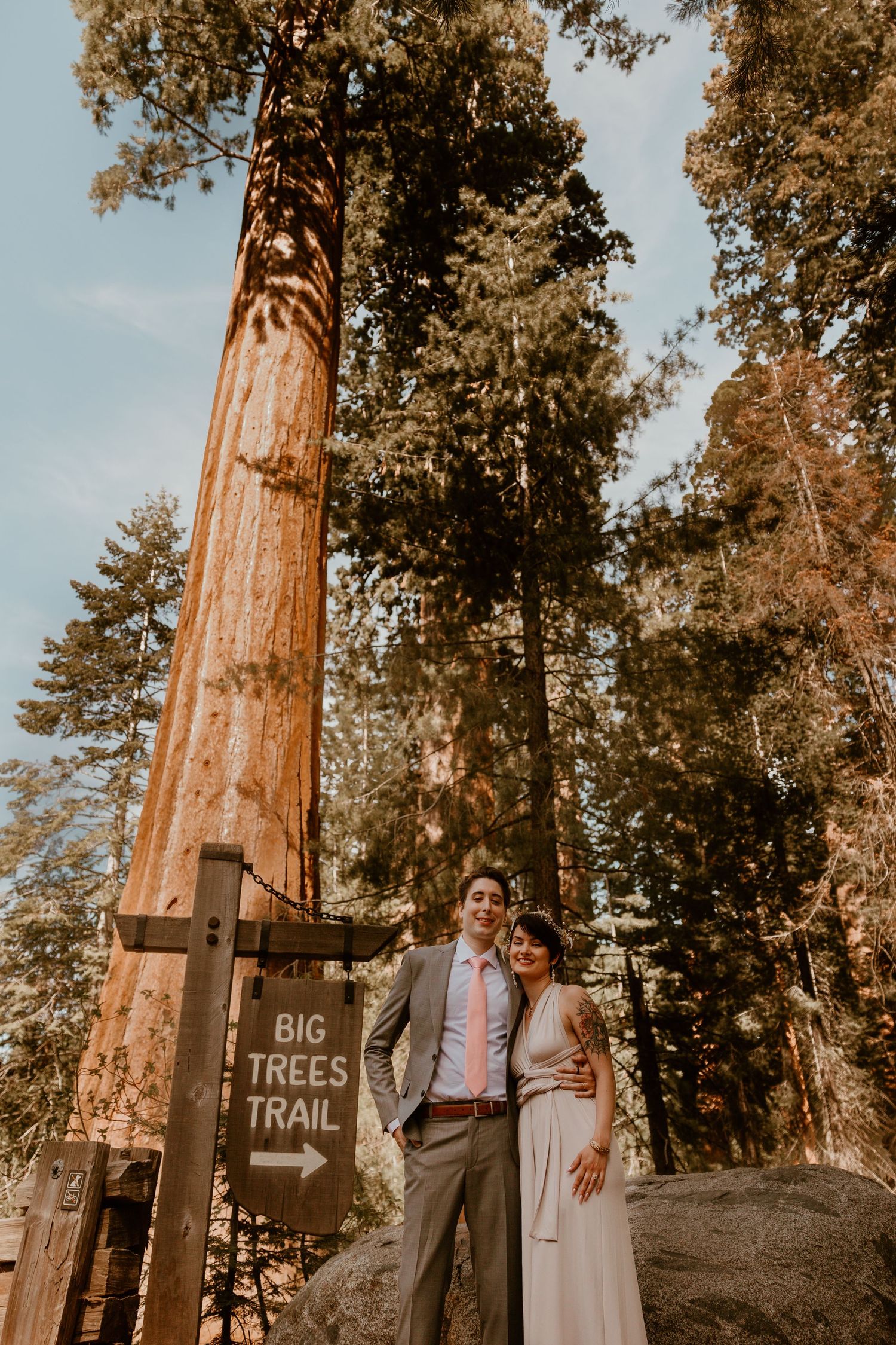 A couple walking hand in hand on a trail marked by wooden directional signs.