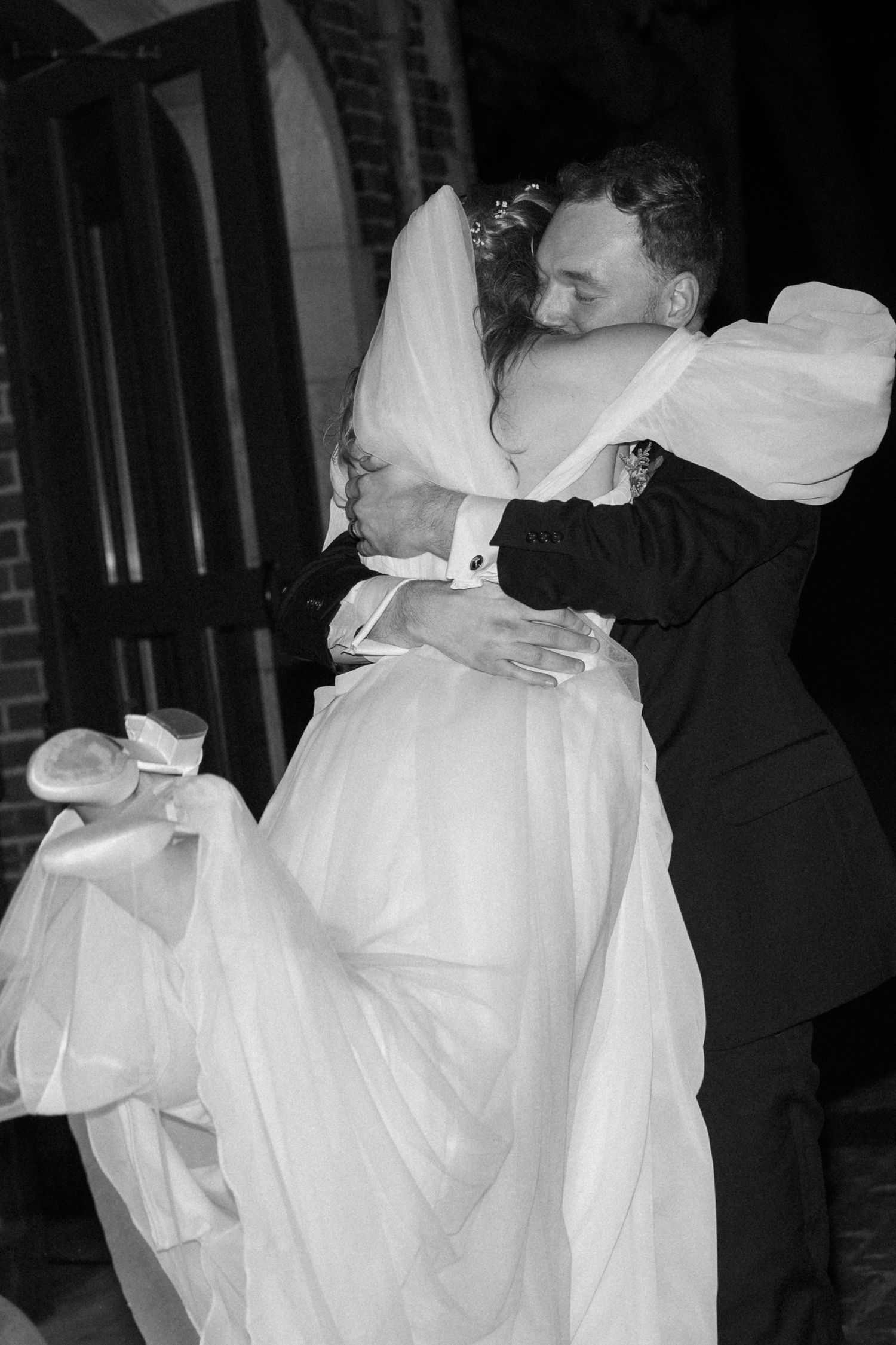 Black and white photo of couple dancing with bride's dress flowing in motion.