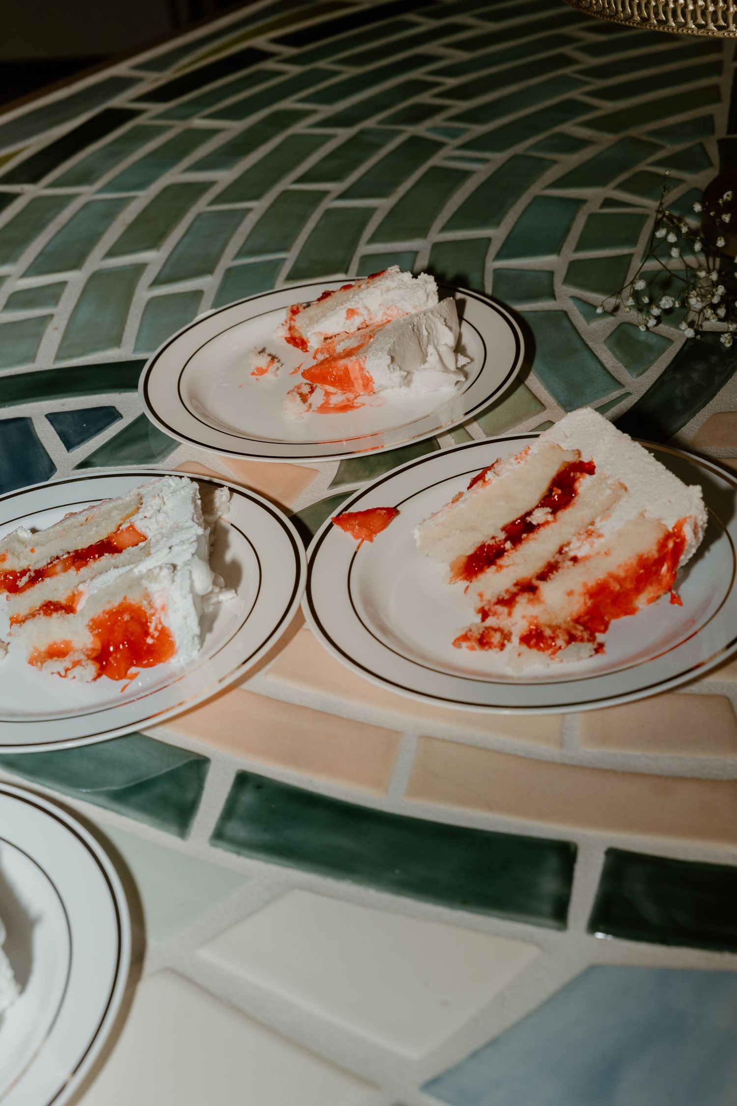 Used plates with smeared wedding cake frosting and crumbs on a patterned tablecloth.