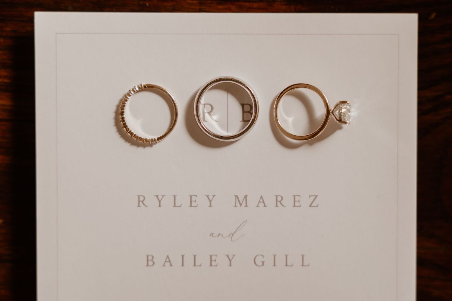 Wedding rings photographed on white paper with elegant text below.