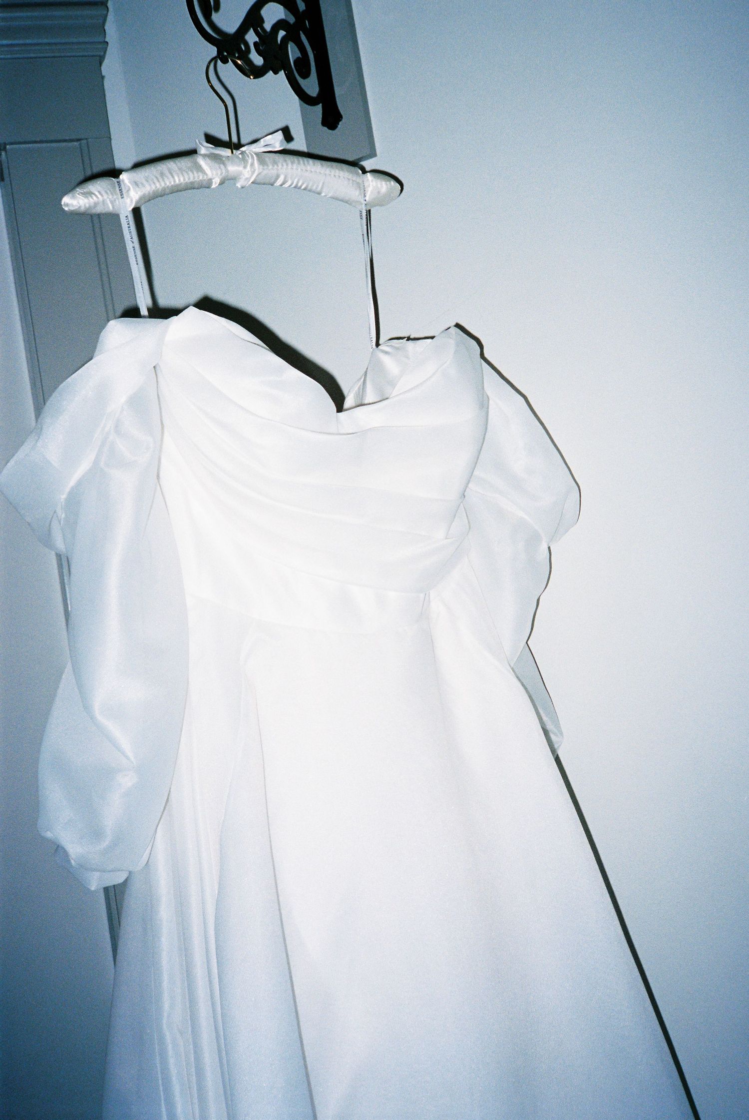 White wedding dress hanging on display against a light blue background.
