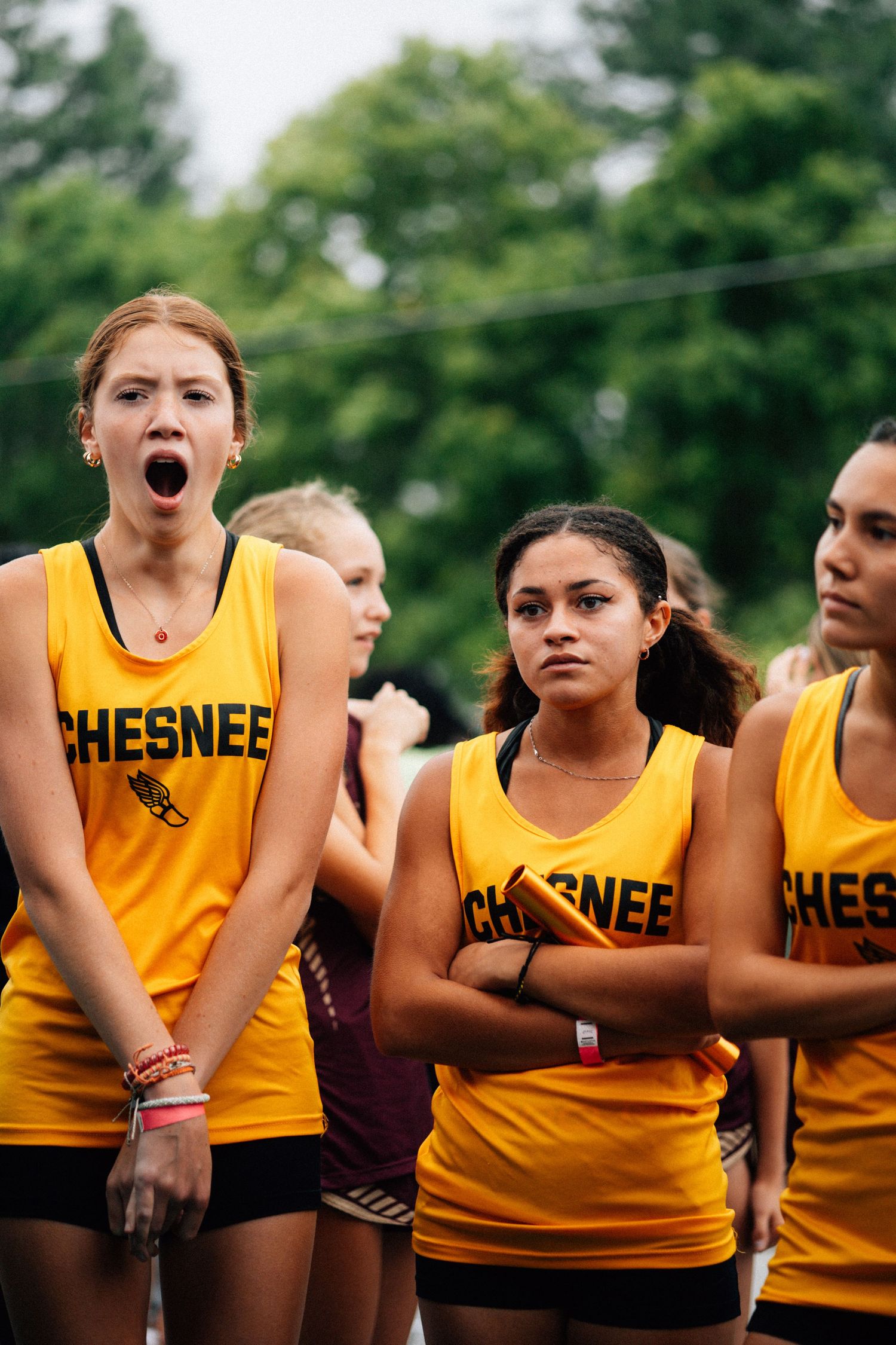 High school track team athletes in yellow Chesnee uniforms showing team spirit during competition.