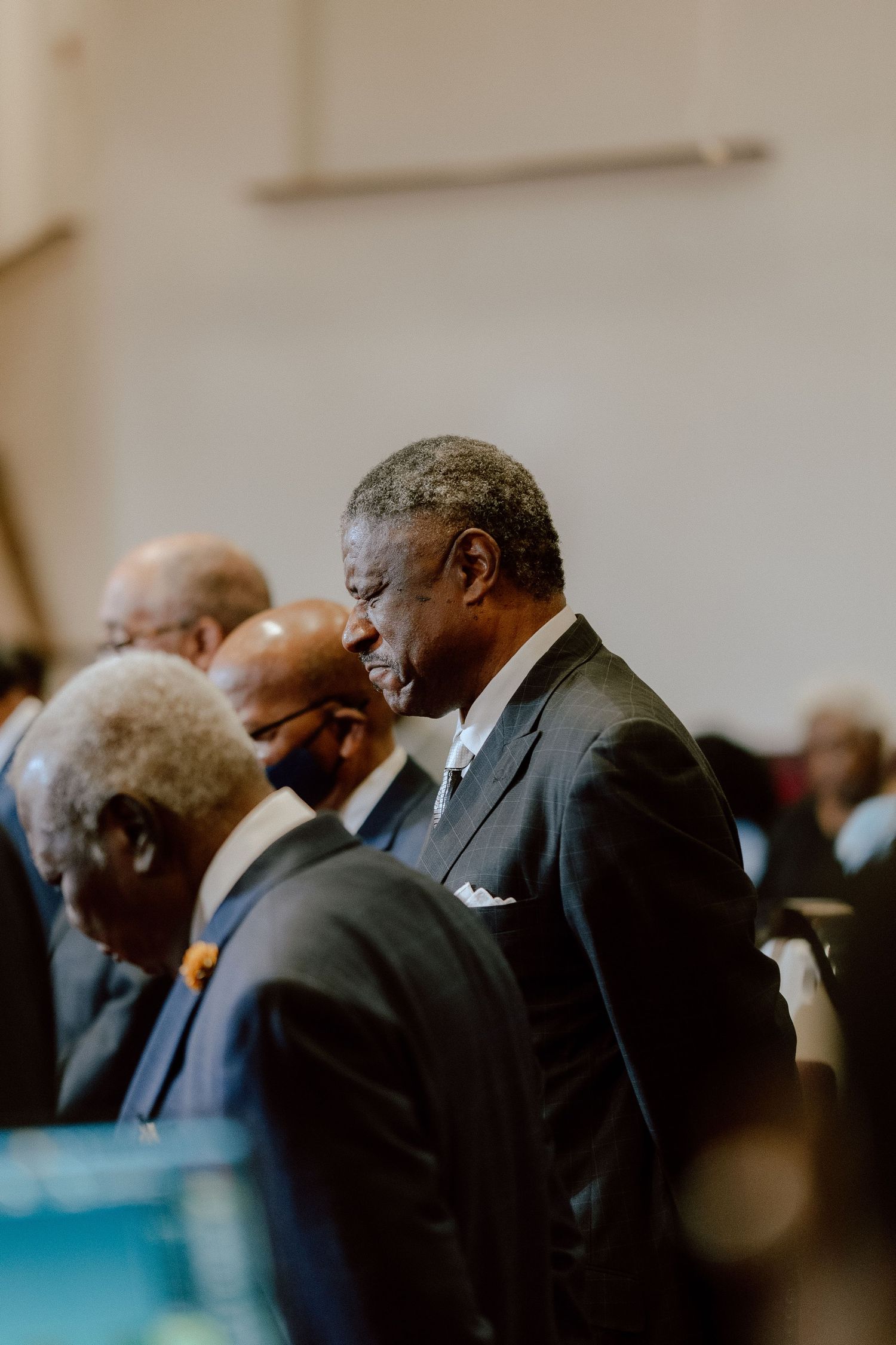 Several people in formal black attire sit at a table during what appears to be a professional gathering or event.
