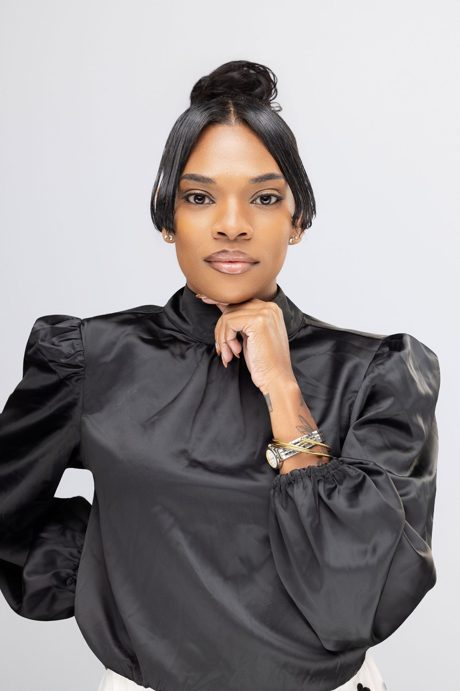 Professional studio portrait series showing a person in a black satin blouse against a light gray background.