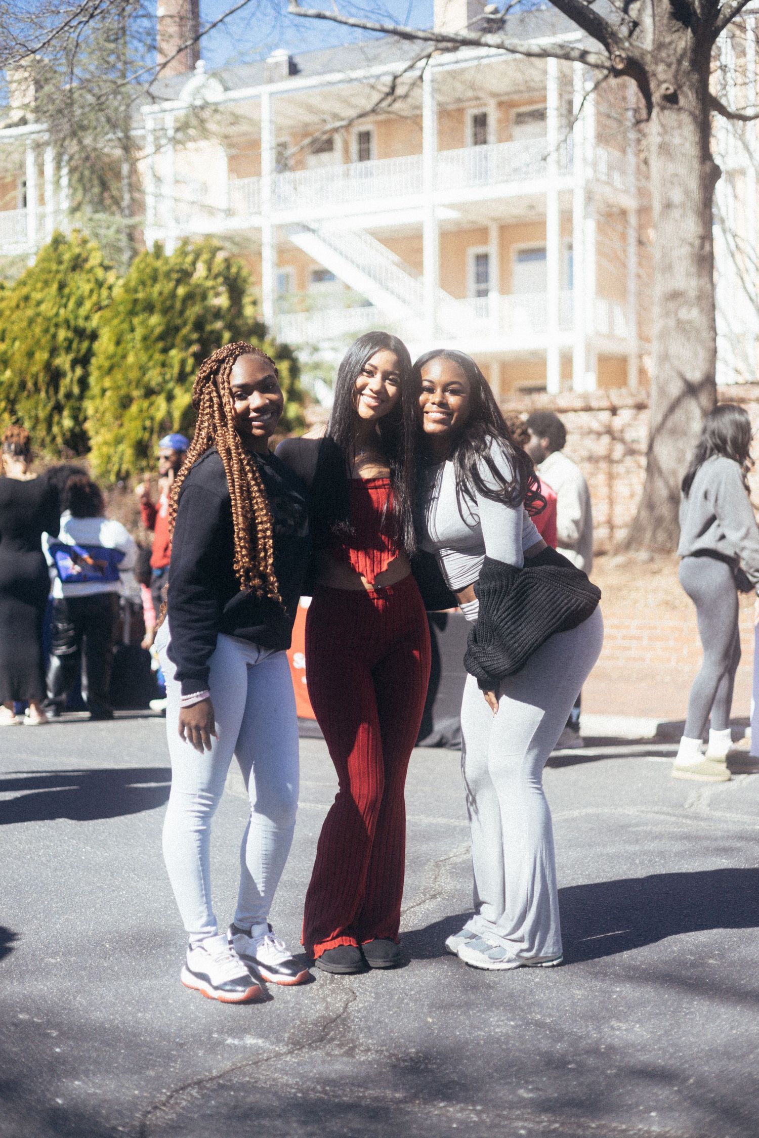 Three people pose together outdoors on a sunny day with a white building and trees in the background. USC Hip Hop Wednesday