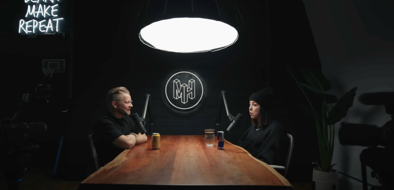 A dark conference room with glowing lights illuminates a long wooden table and chairs in a modern office setting.
