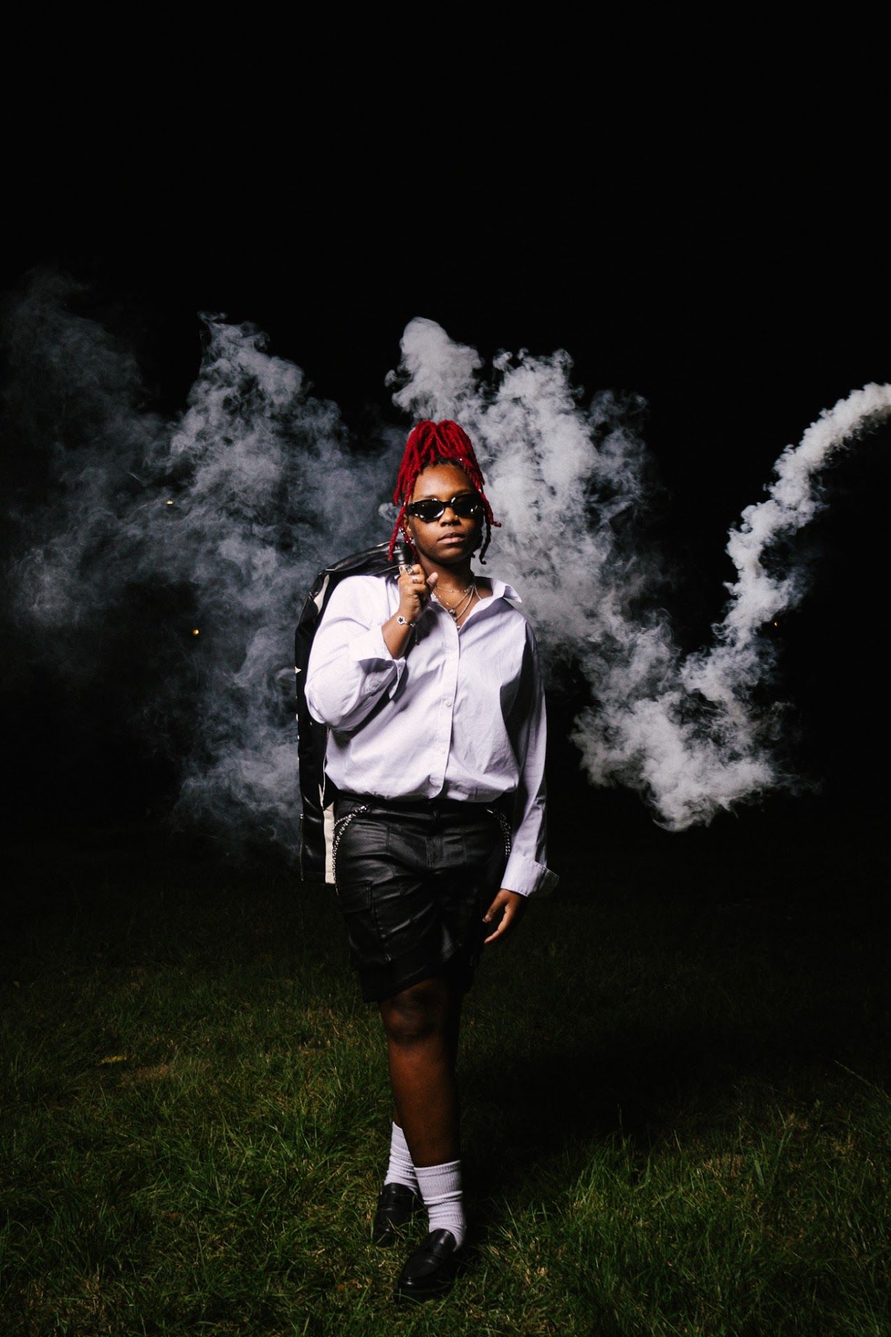 Artistic dark outdoor portrait series with white smoke effects and formal attire on grassy background creating moody atmosphere.