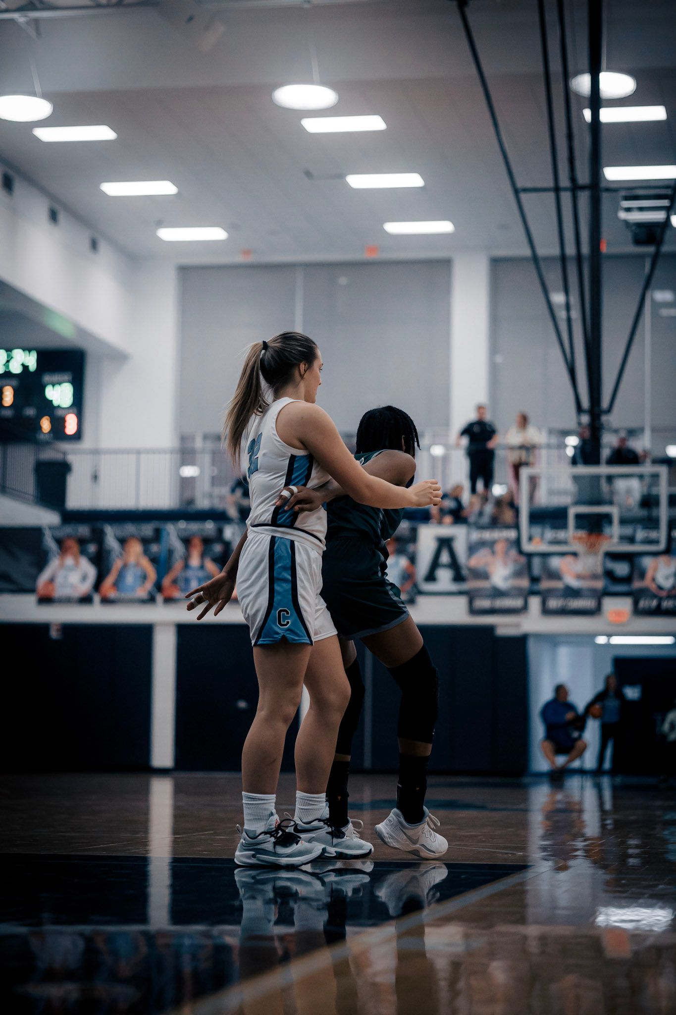 Two basketball players battling for position during competitive game on indoor court.
